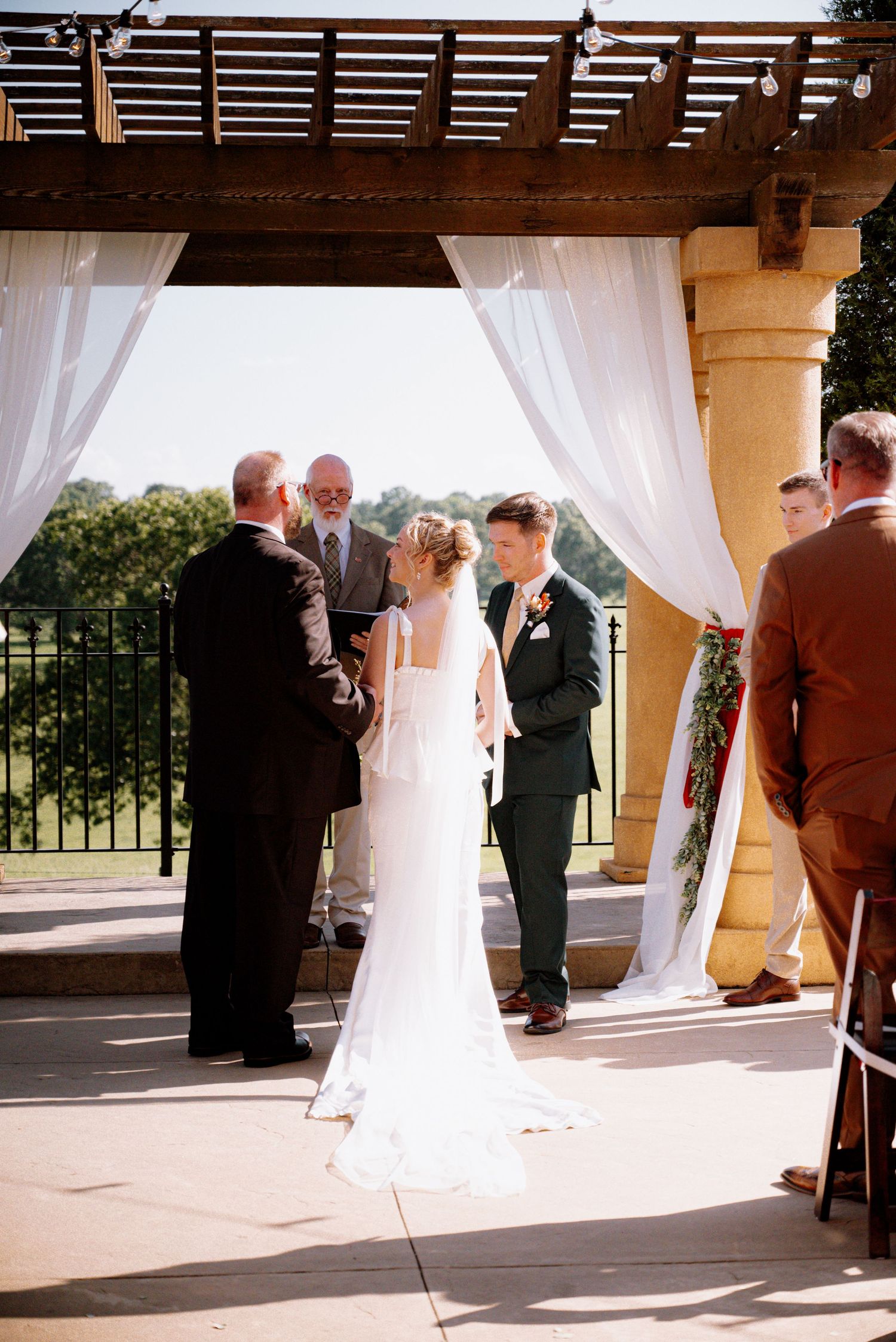 Bride and groom standing at the alter at their outdoor ceremony, surrounded by friends & family.