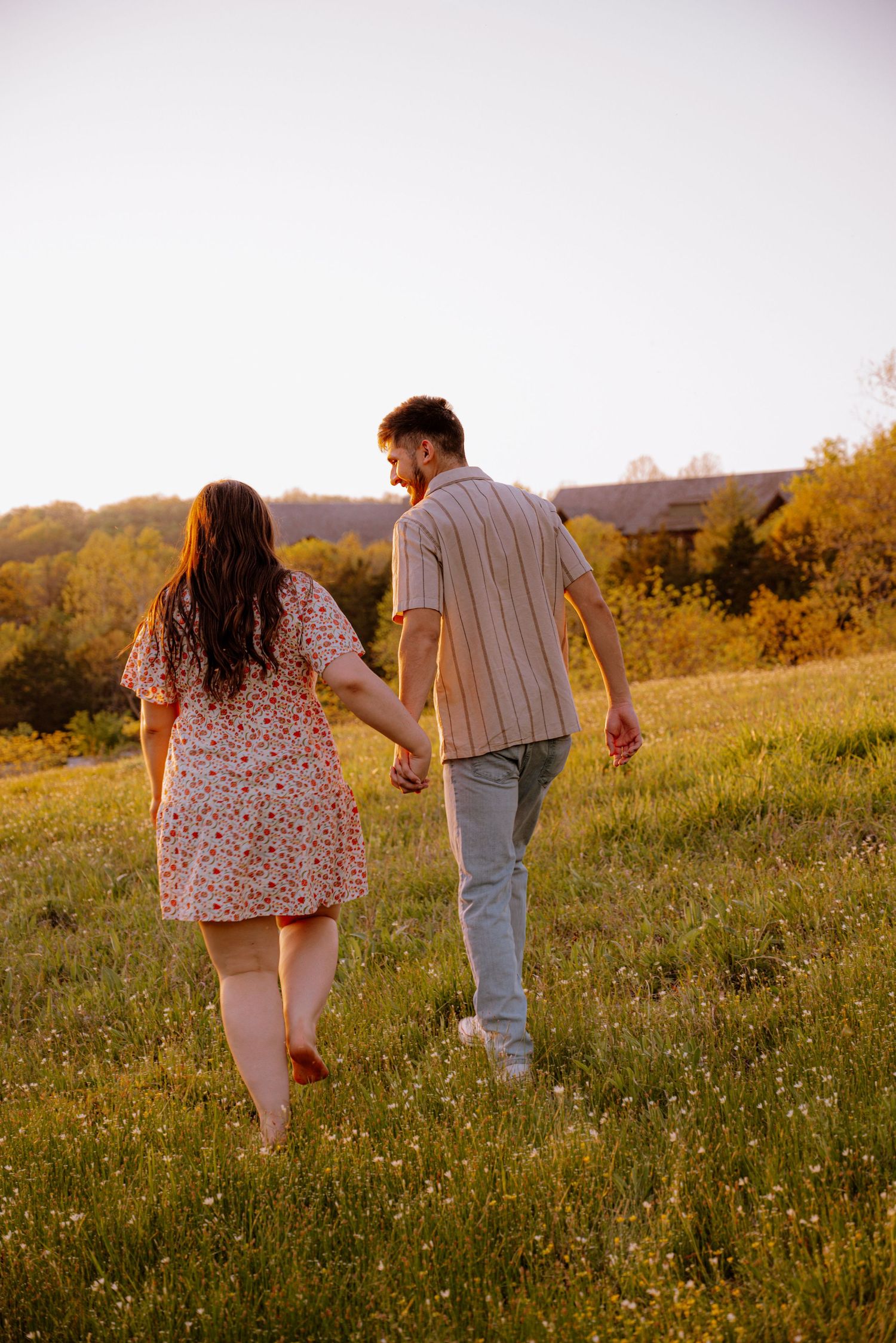 Couple posing for a photo while they hold hands and walk in front of a beautiful view.