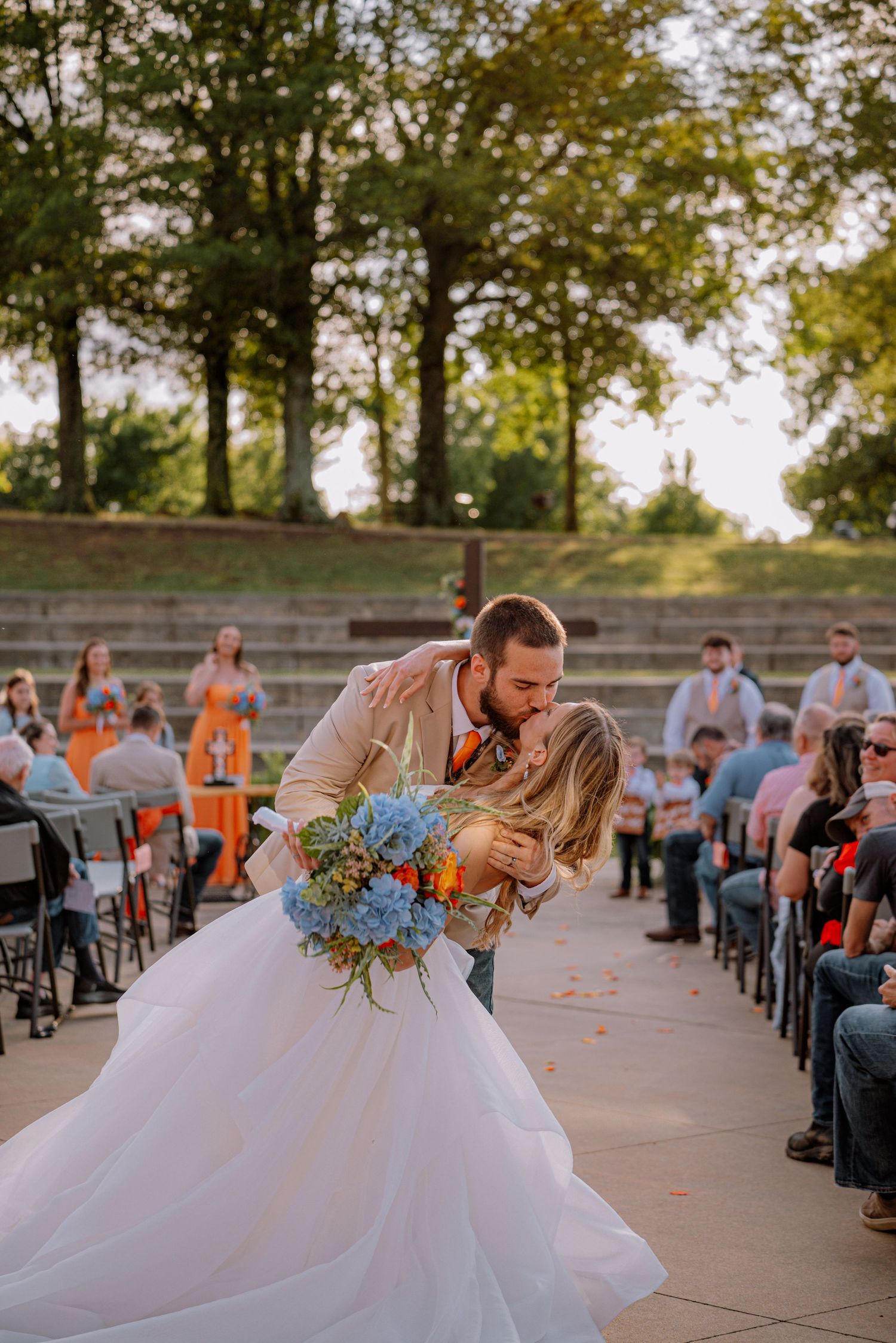 Bride and groom kissing in the aisle, surrounded by friends and family.