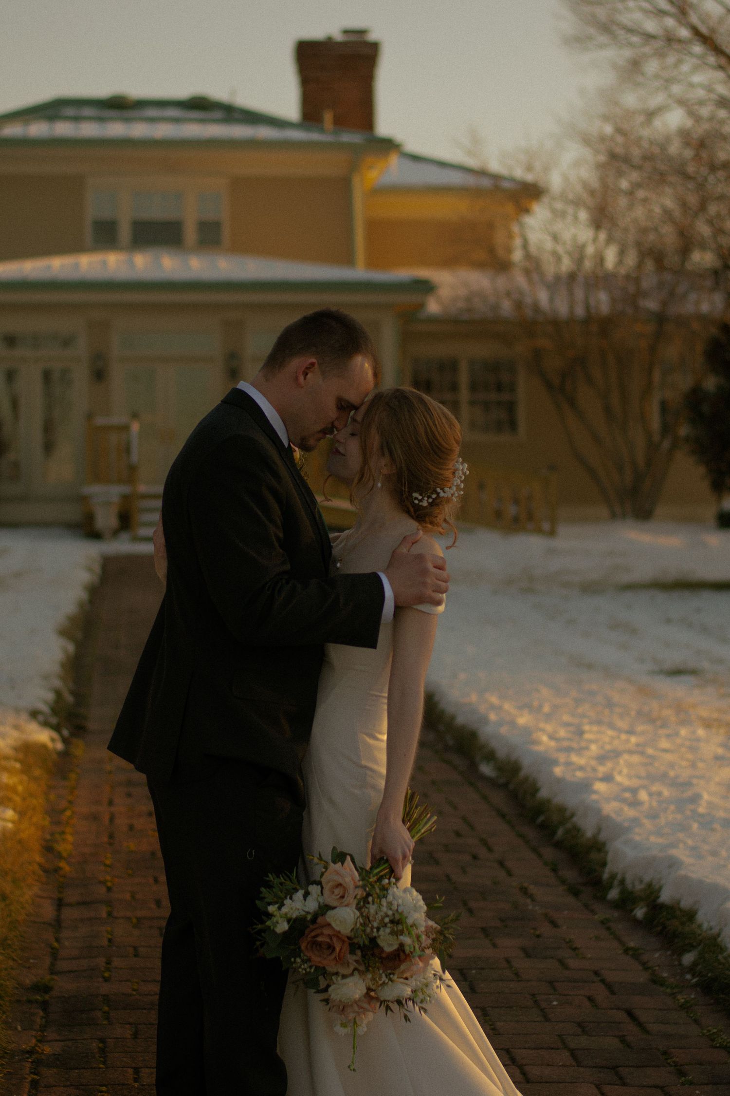 Bride and groom standing posing for a bridal portrait on a beautiful plantation, surrounded by snow and light.