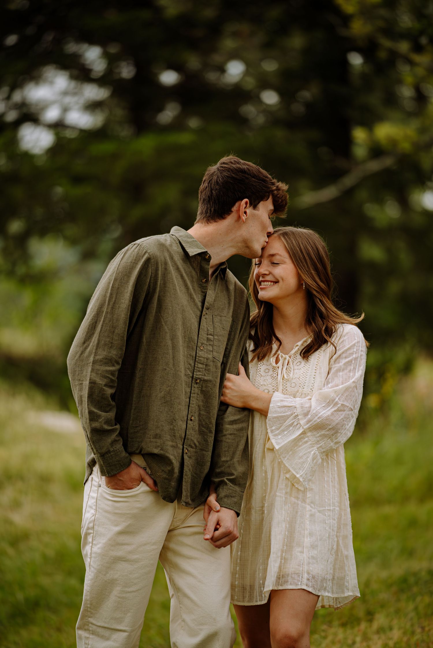 Couple posing for a photo while they kiss in front of a beautiful view.