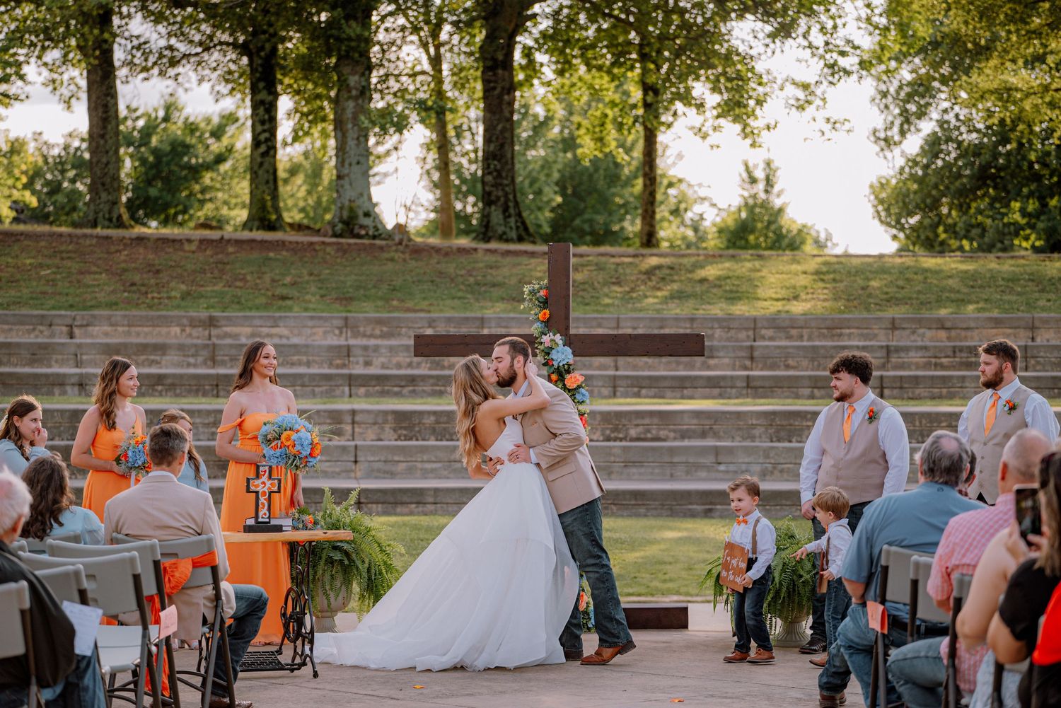 Bride and groom kissing at the altar, surrounded by bridesmaids and groomsman.