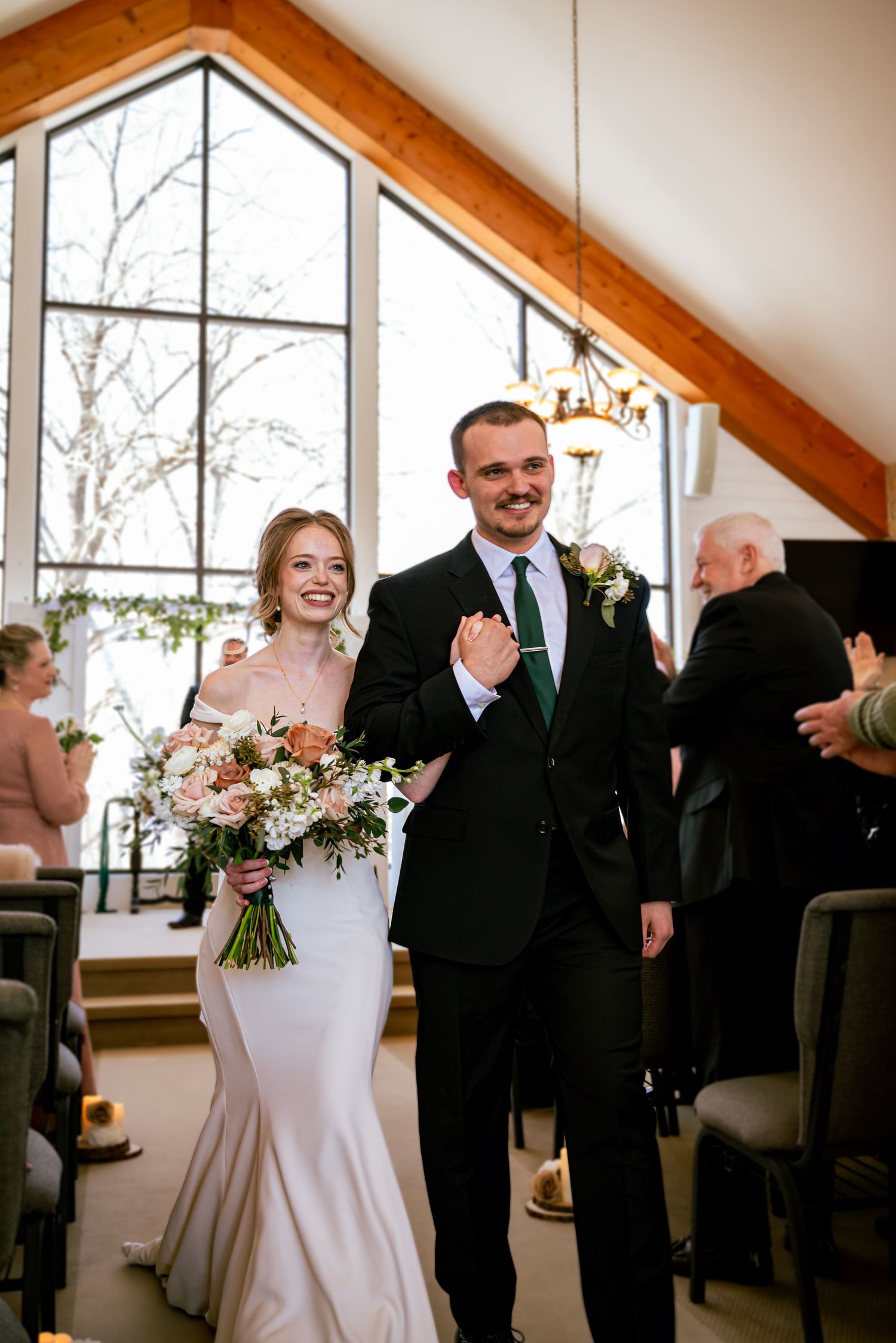 Bride and groom walking together down the aisle at their home church, surrounded by family.