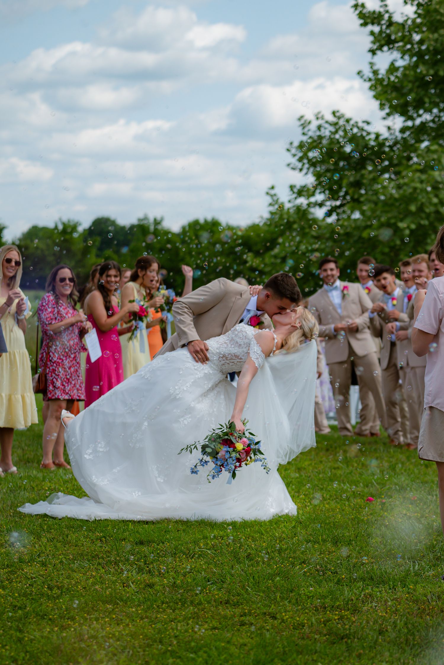 Bride and groom kissing on the ceremony isle, surrounded by friends and family.