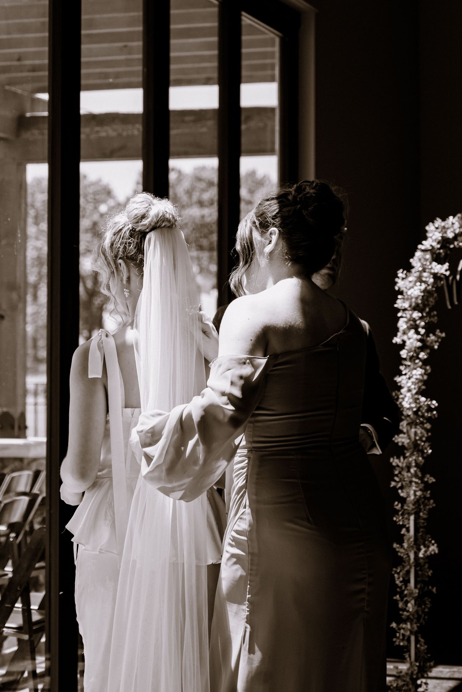 Bride and maid of honor photo sharing a moment by the window that outlooks the place where the ceremony will be held.