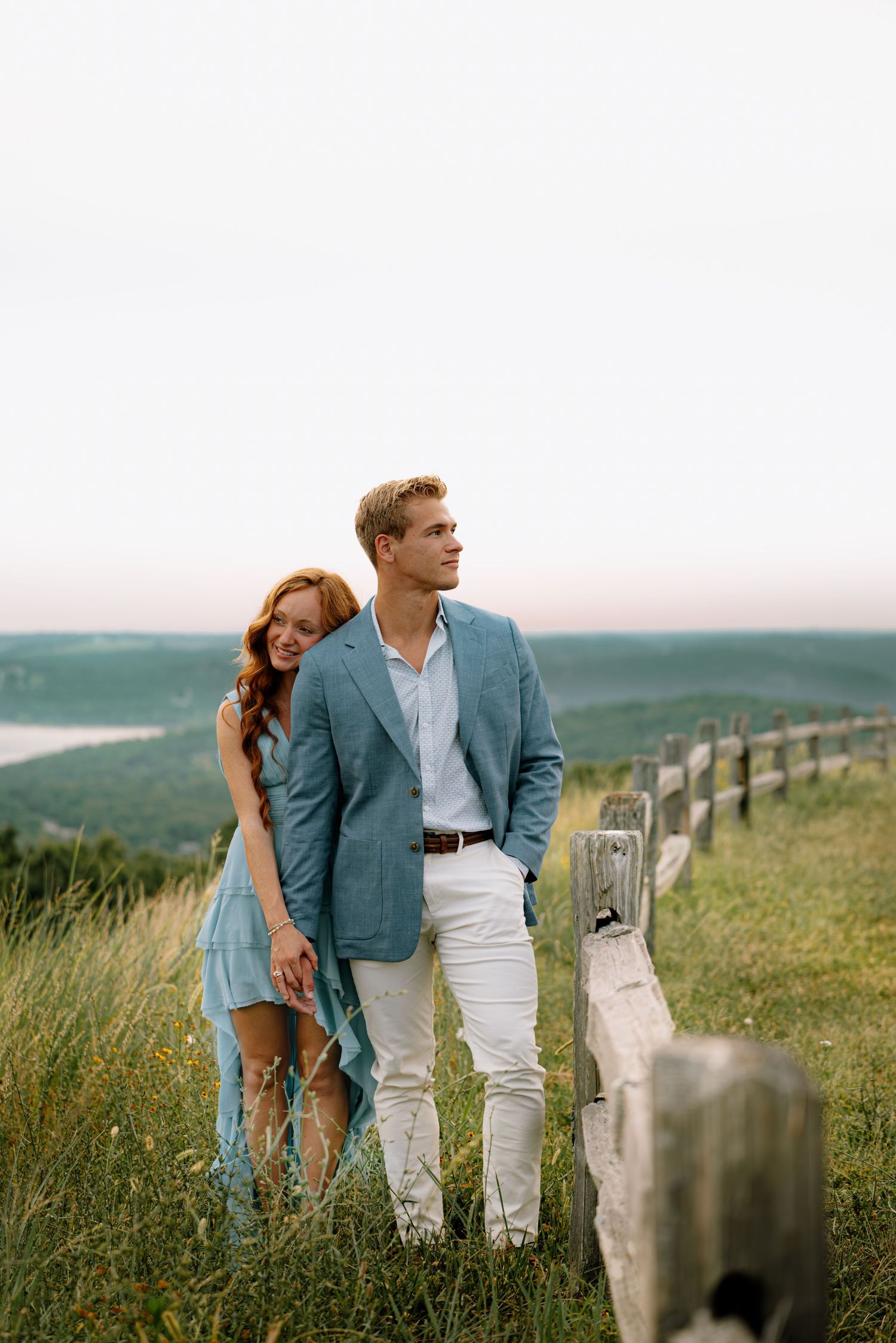 Couple posing for a photo while they embrace in front of a beautiful view.