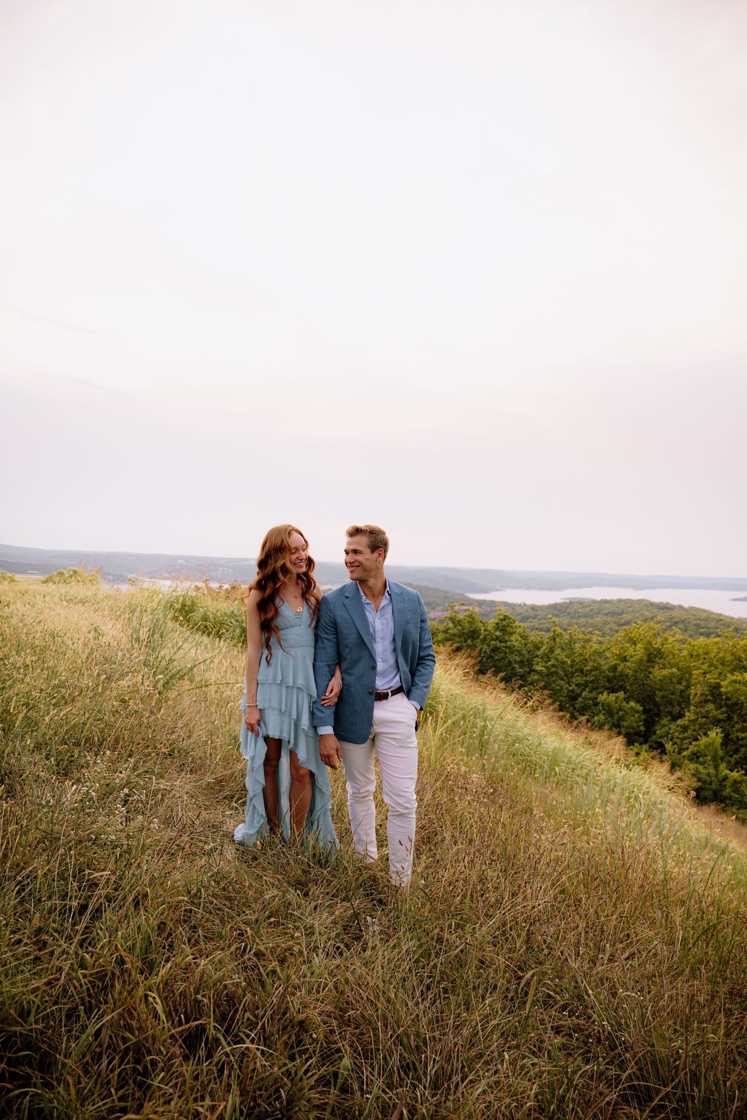 Couple smiling as they stand in a field while holding hands