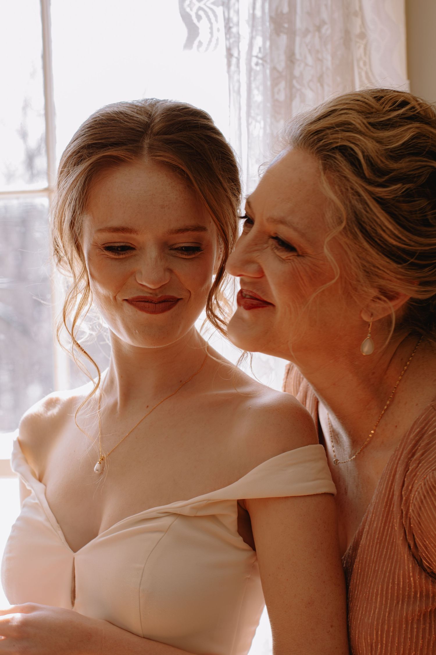 Mother and bride sharing a sweet moment by a window