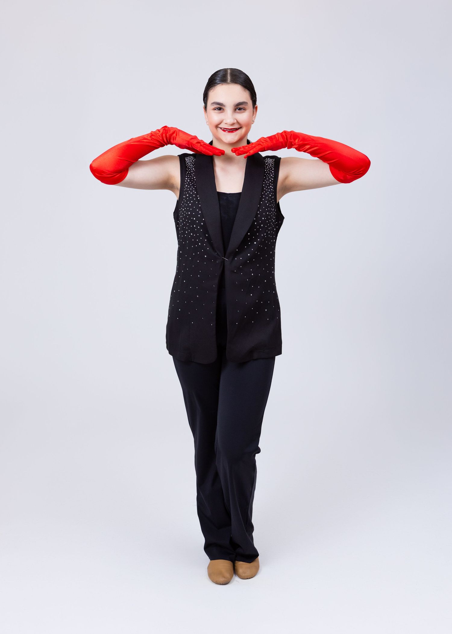 Young woman in black rhinestone vest and red opera gloves strikes a theatrical pose.