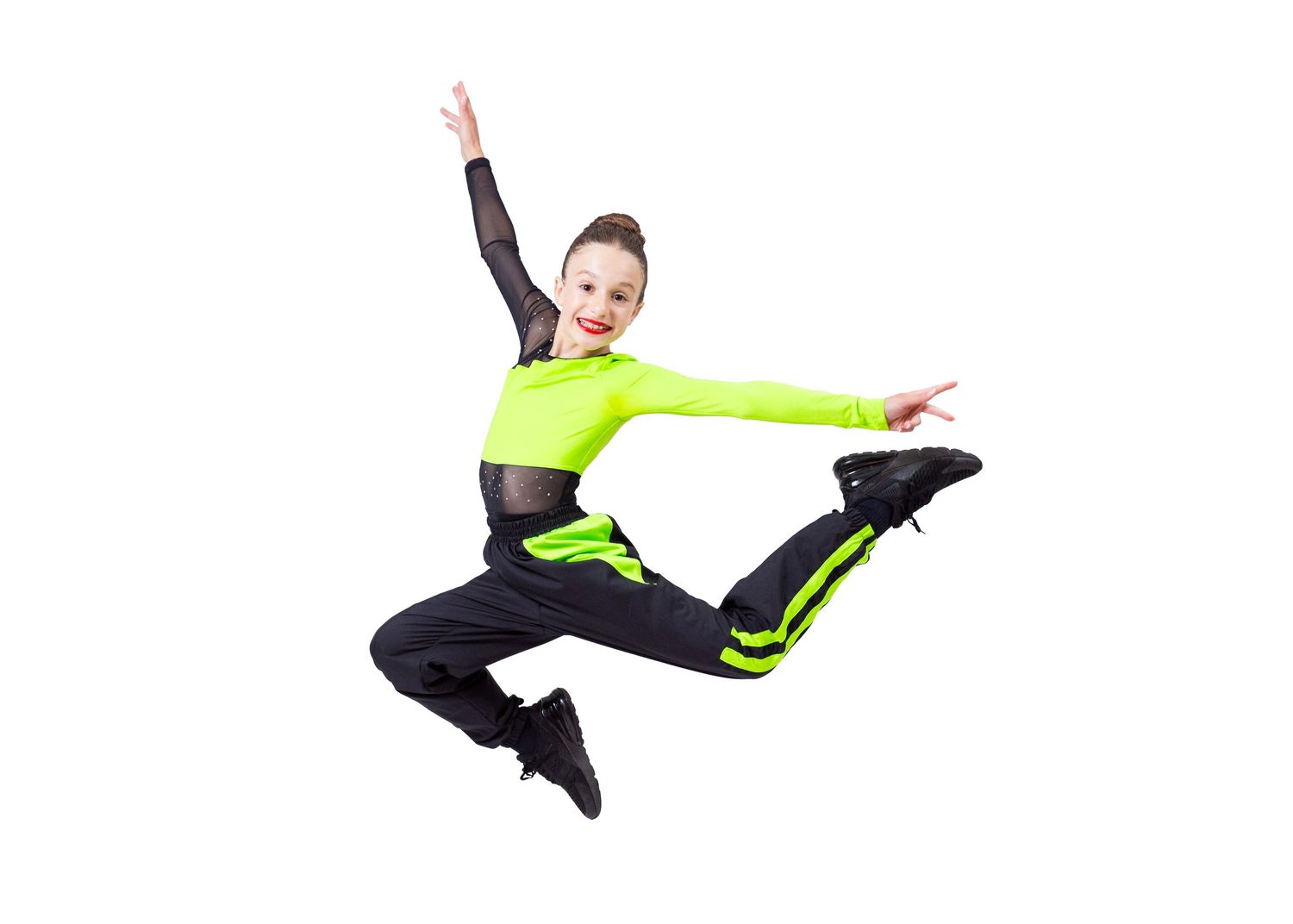 Athletic girl jumping in neon green crop top and black pants on white studio background.