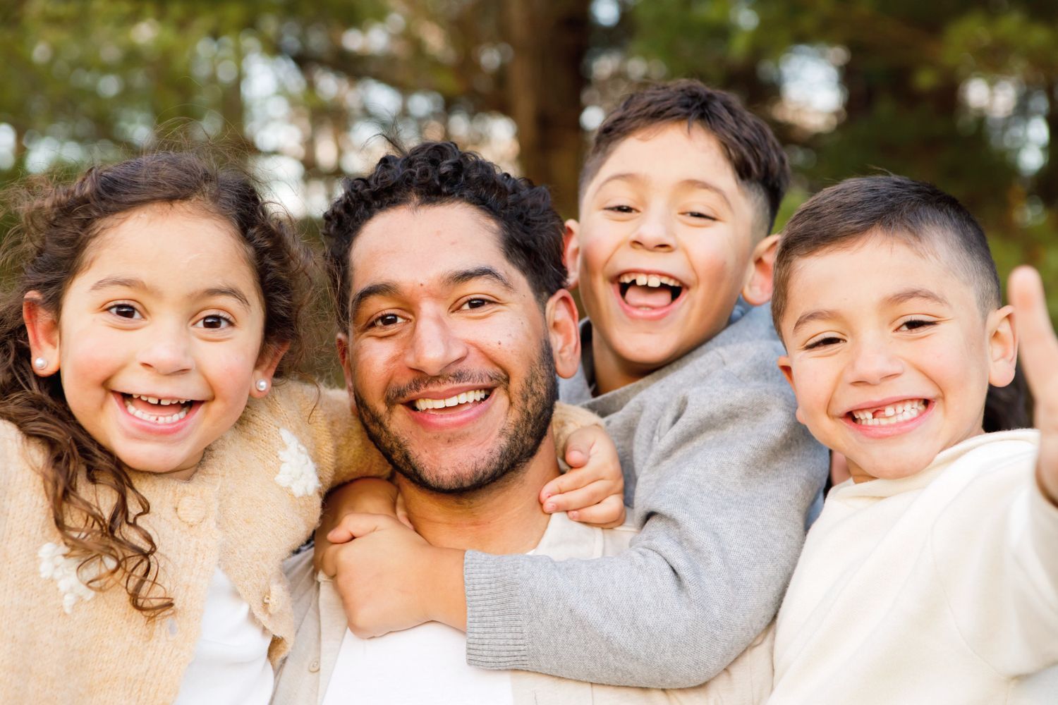 Smiling father and three happy children posing together outdoors.