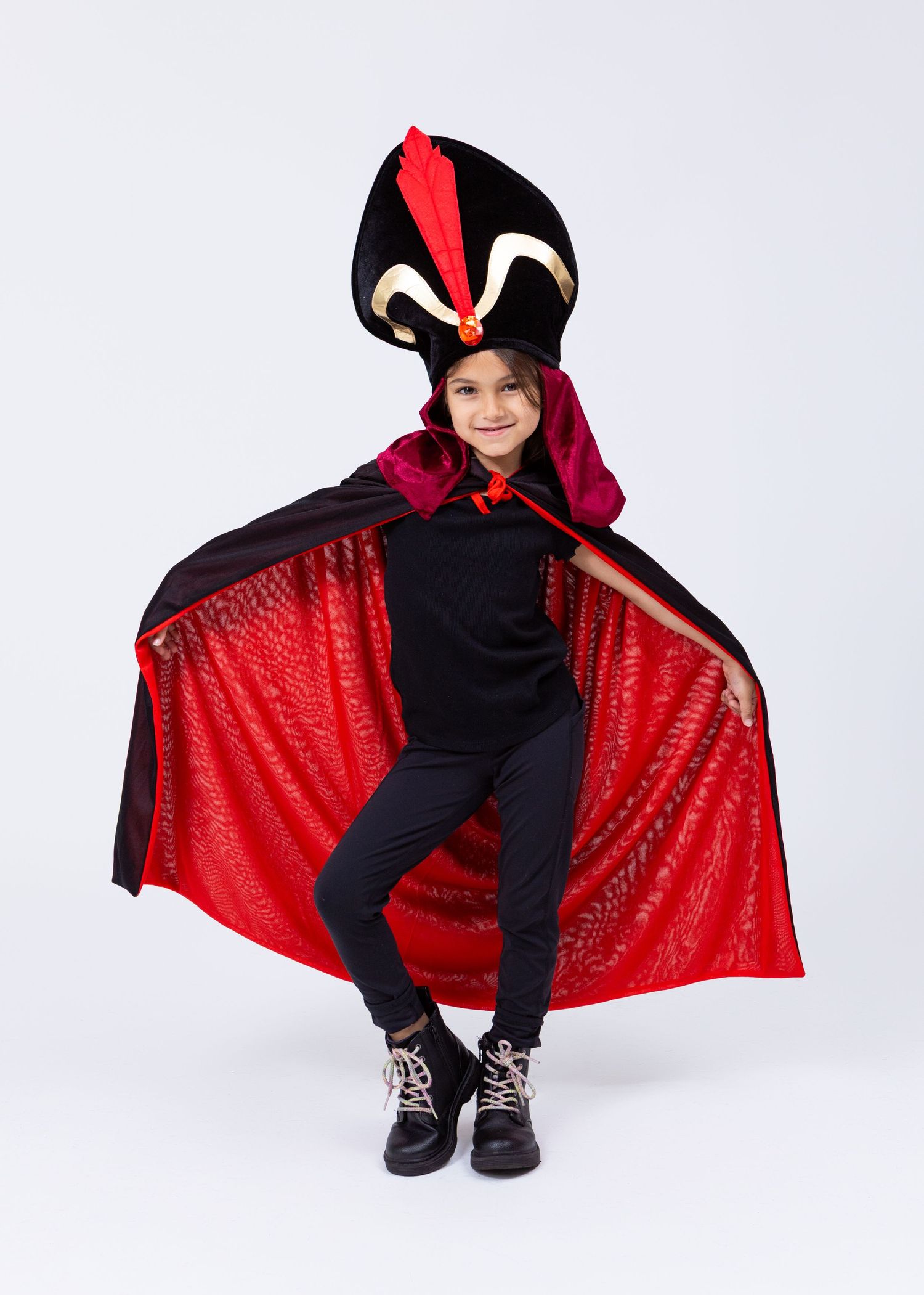Young girl dressed as Jafar in black and red cape costume with tall hat poses dramatically.