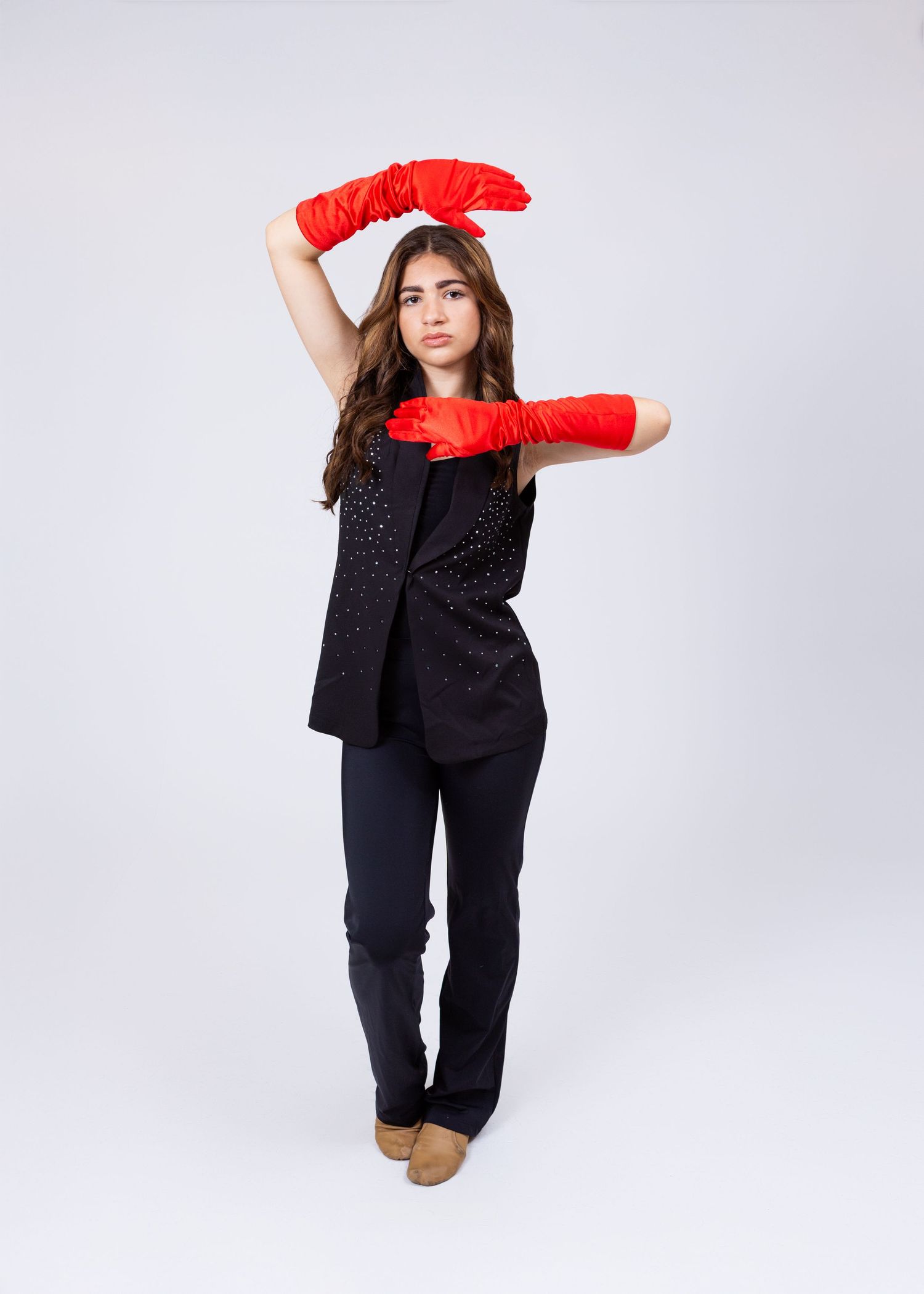 Teen dancer in black outfit with red long gloves performs expressive contemporary dance pose.