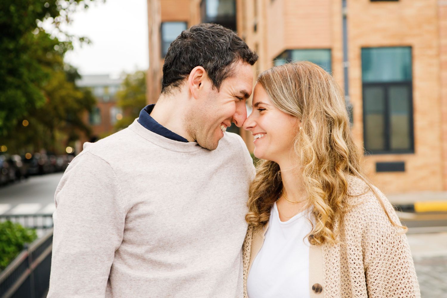 Couple smiling and touching foreheads affectionately outdoors in an urban setting.