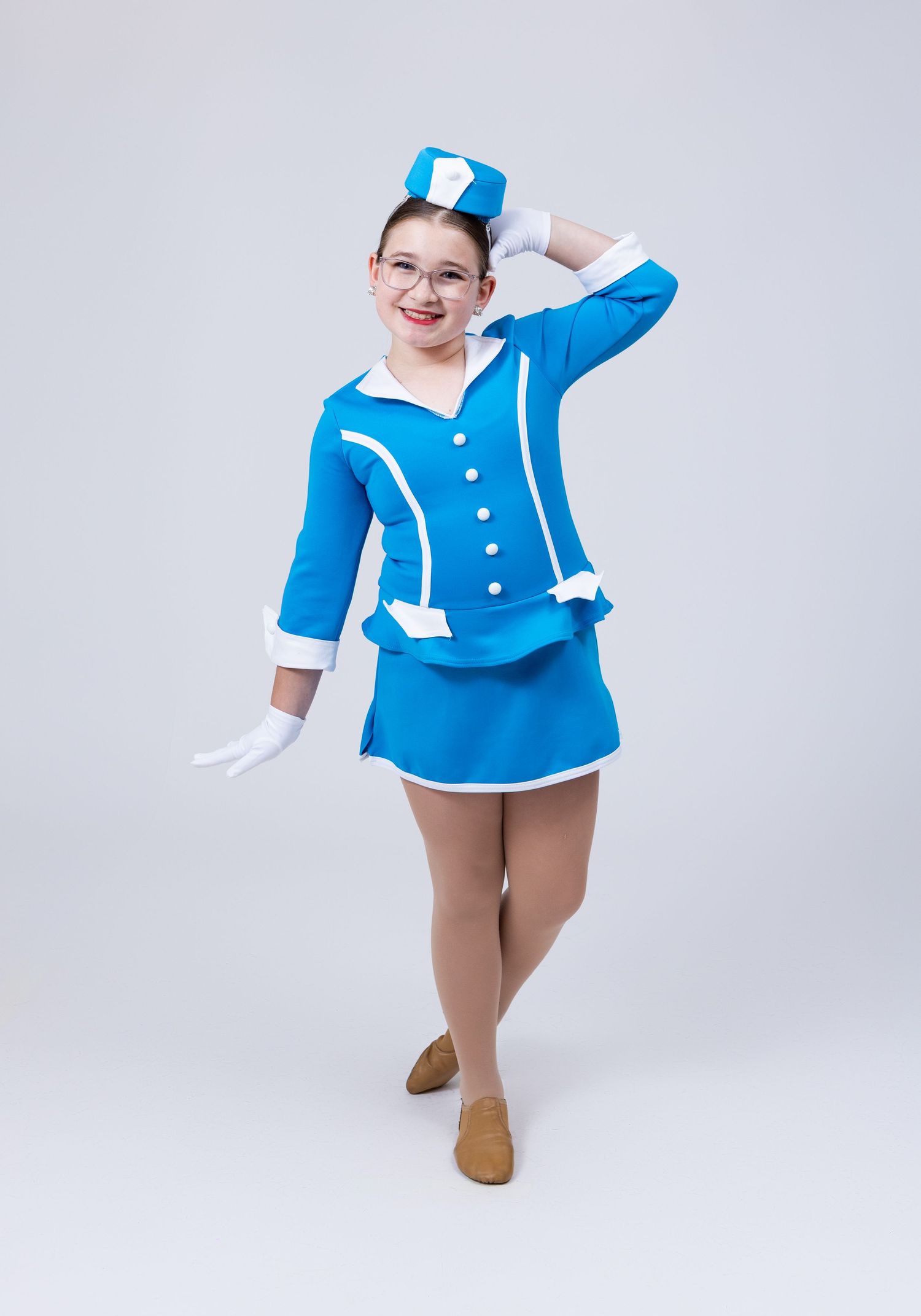 Young girl in blue stewardess dance costume with white gloves and matching hat poses gracefully.