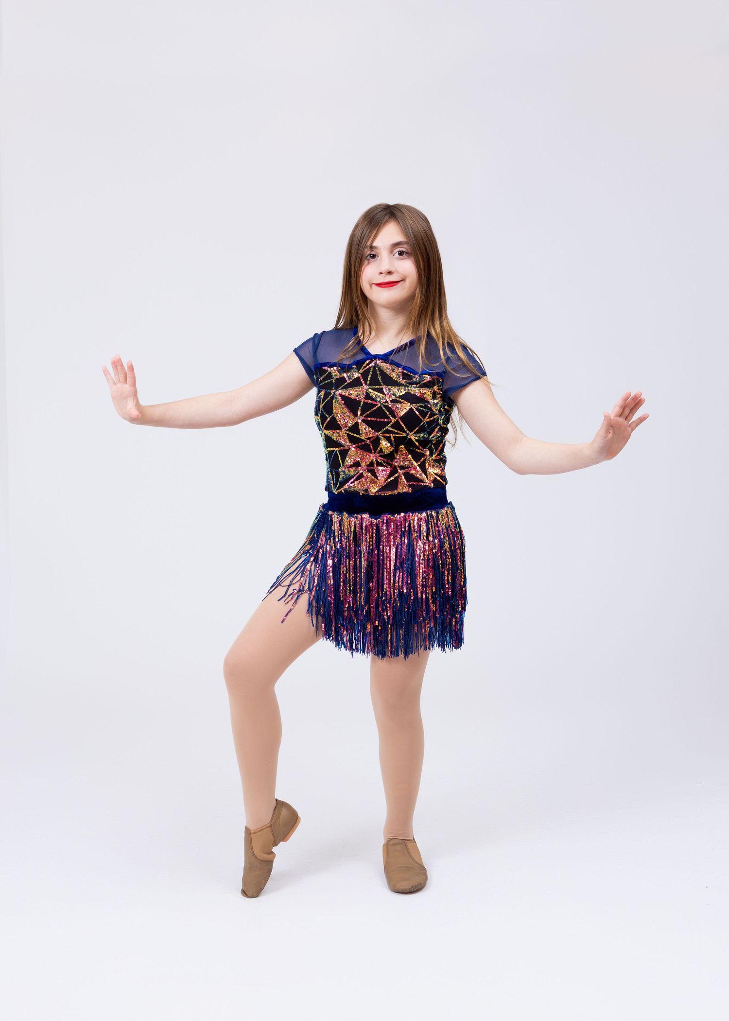A young girl in a navy and multicolor sequined fringe dance costume strikes a jazz dance pose.