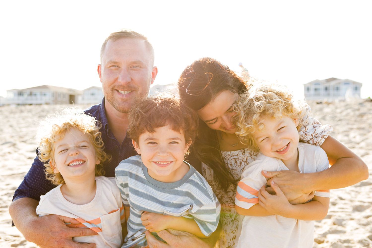 Happy family of five smiling together on a sunny beach.