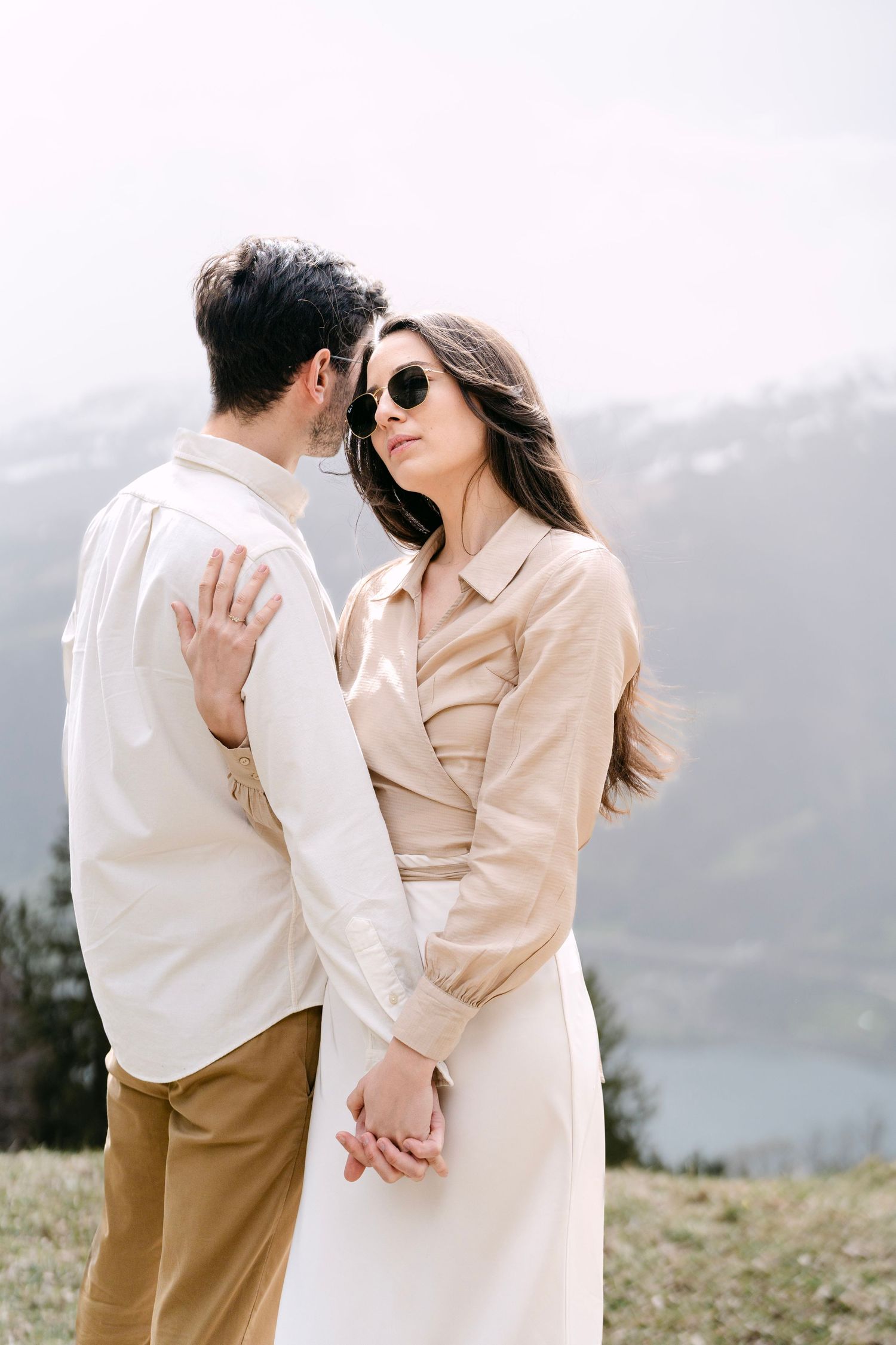 Romantic couple in neutral tones embracing against a mountain backdrop.