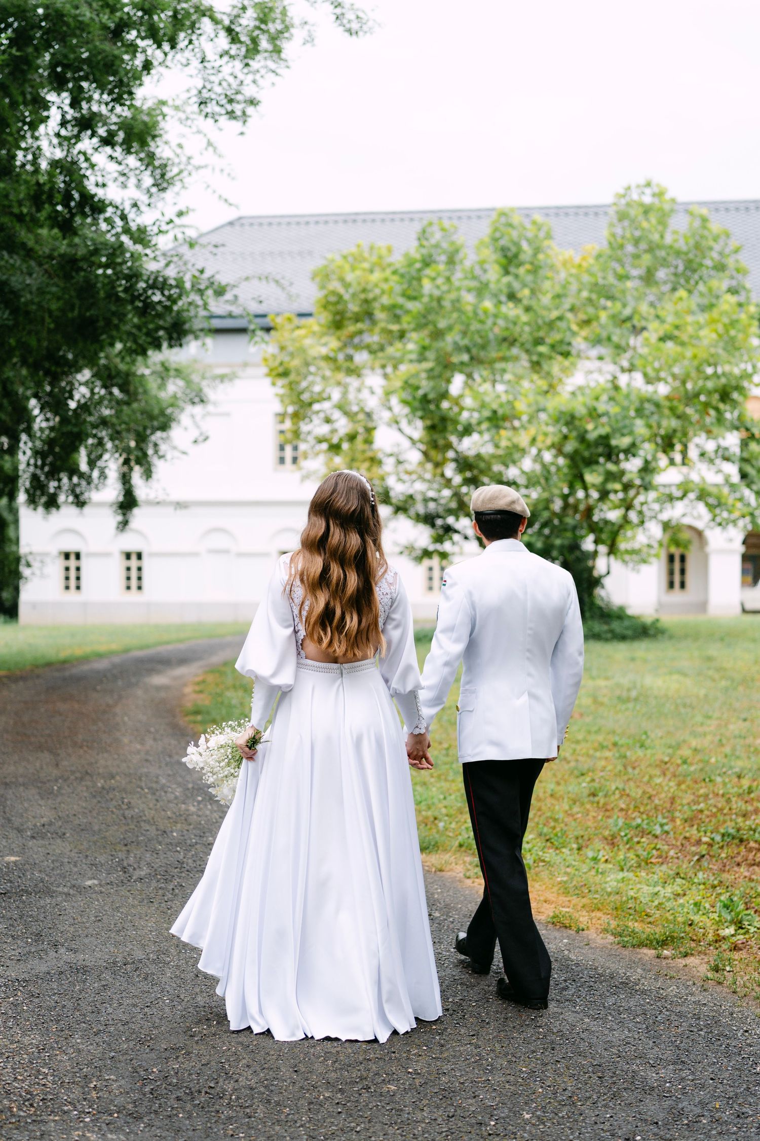 Couple walks together on path near white building.