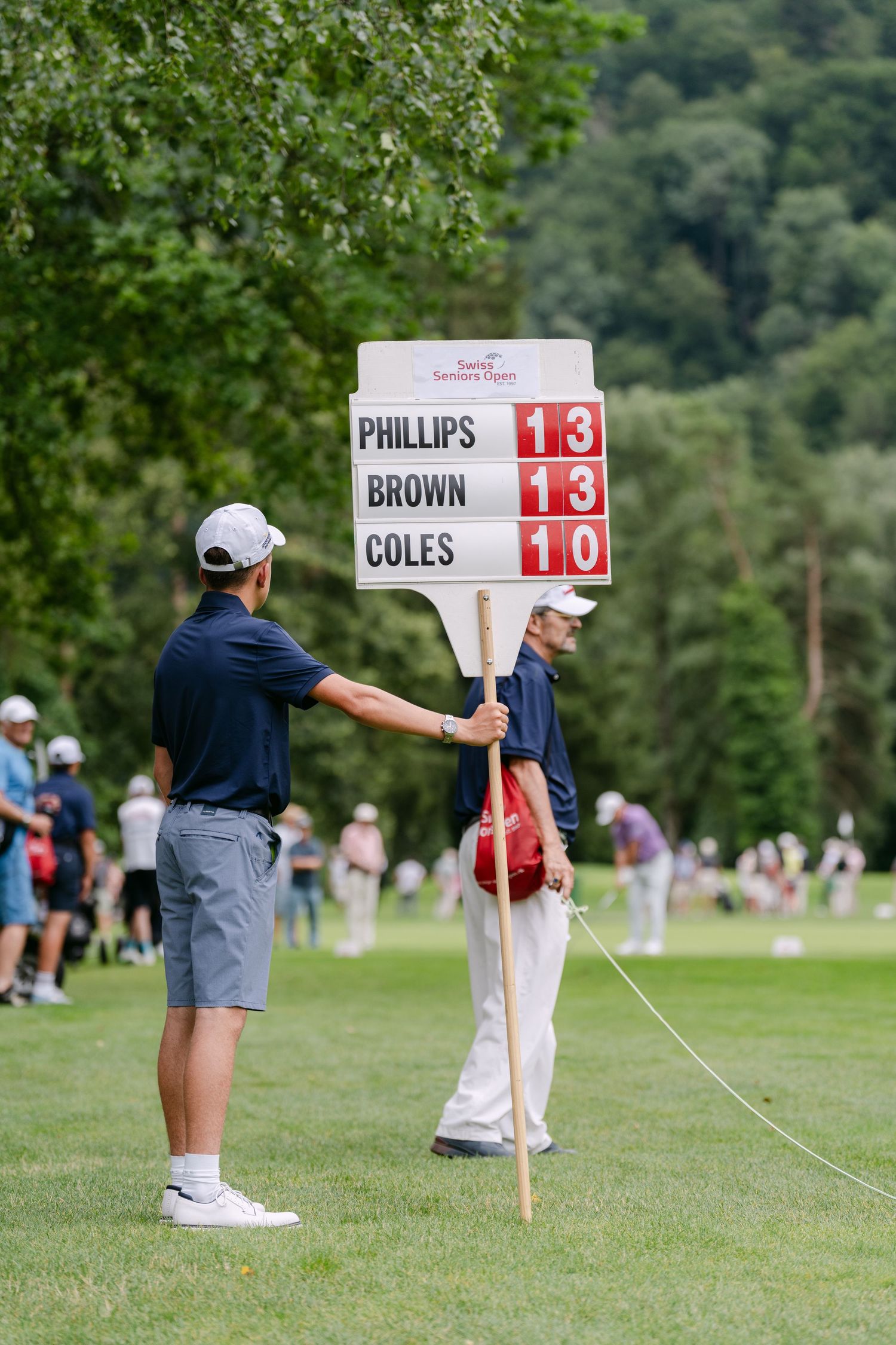 Golf tournament scoreboard showing Phillips and Brown match scores on a grassy course.