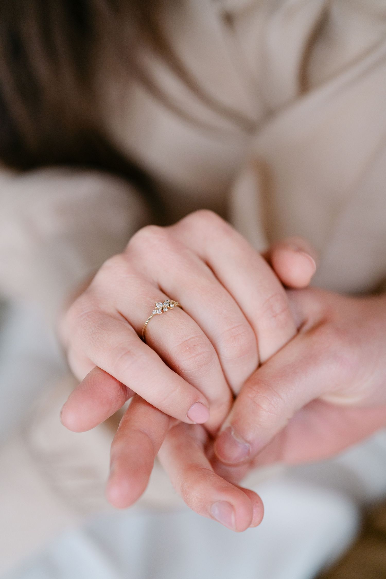 Close-up shots of hands gently intertwined, showing a delicate engagement ring.