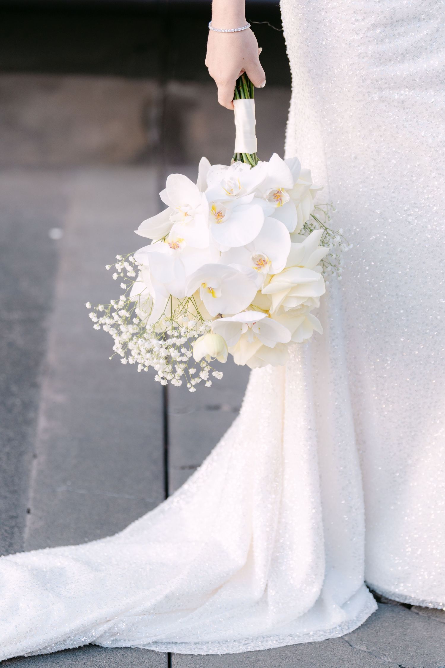Close-up details of white orchids and baby's breath in an elegant bridal bouquet.