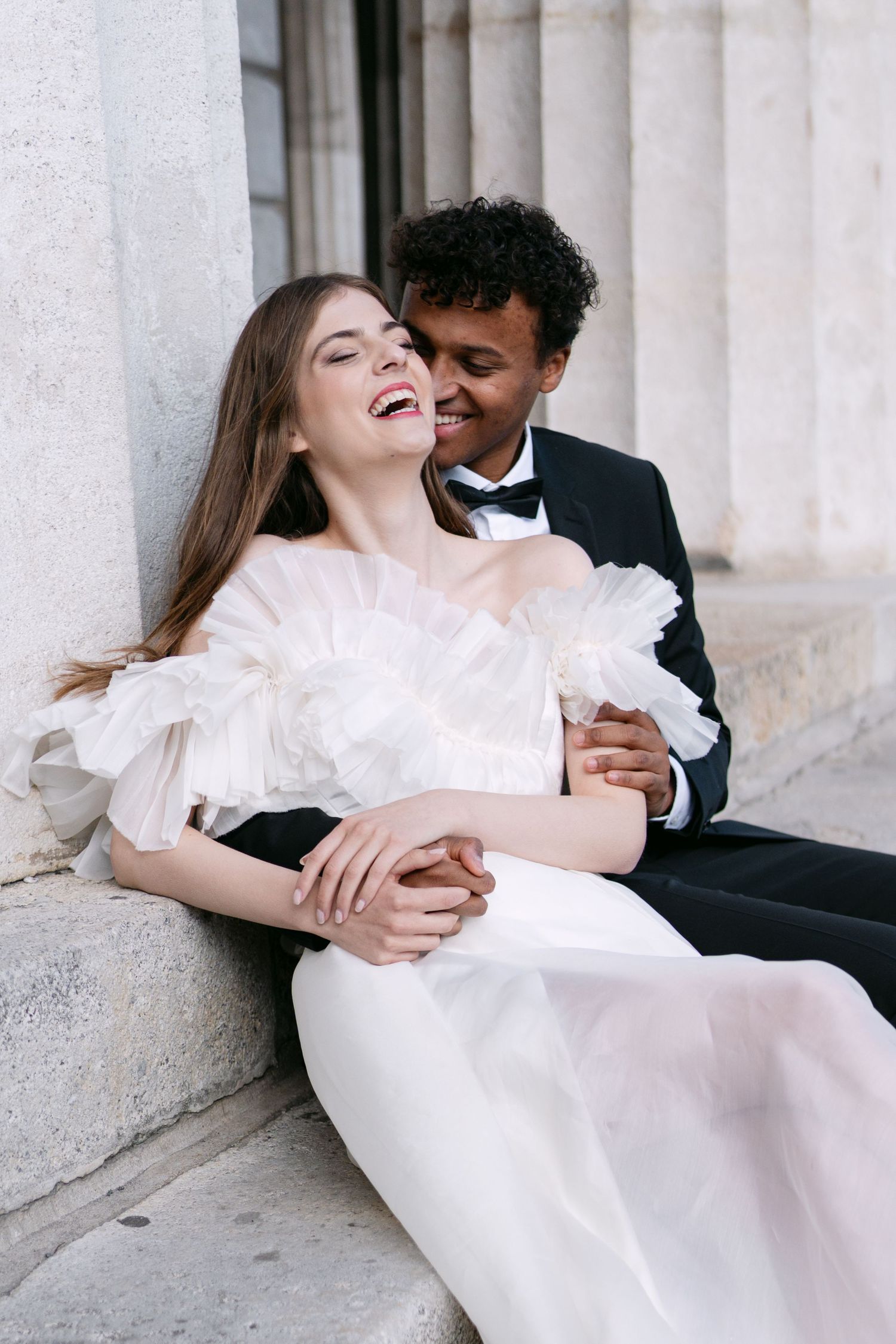 Romantic wedding couple shares joyful moment on stone steps.