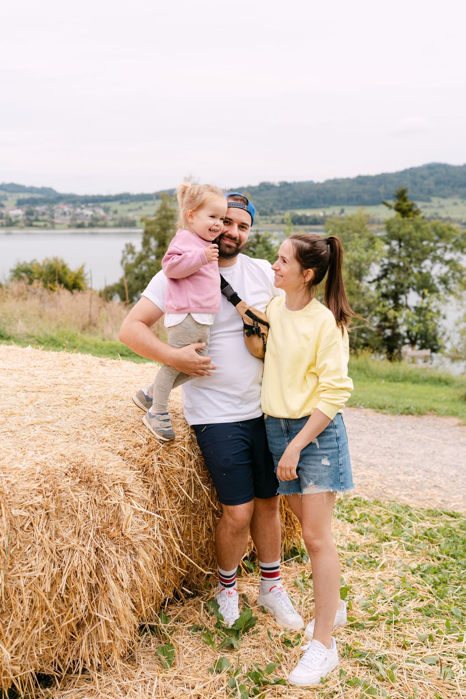 Family moments captured by hay bales with mountains and water in the background.