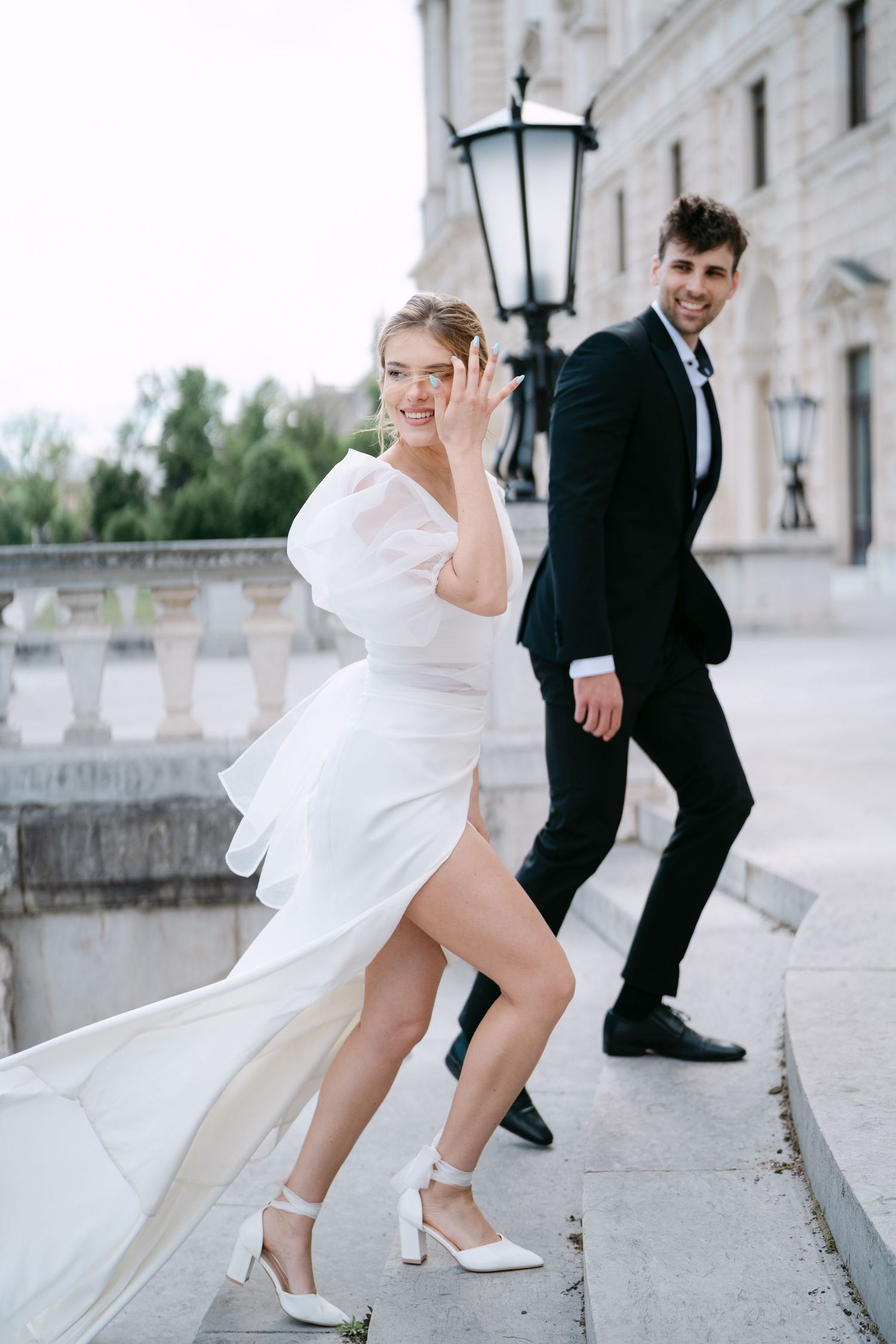 Playful wedding photo shoot on an ornate balcony with classic architecture.