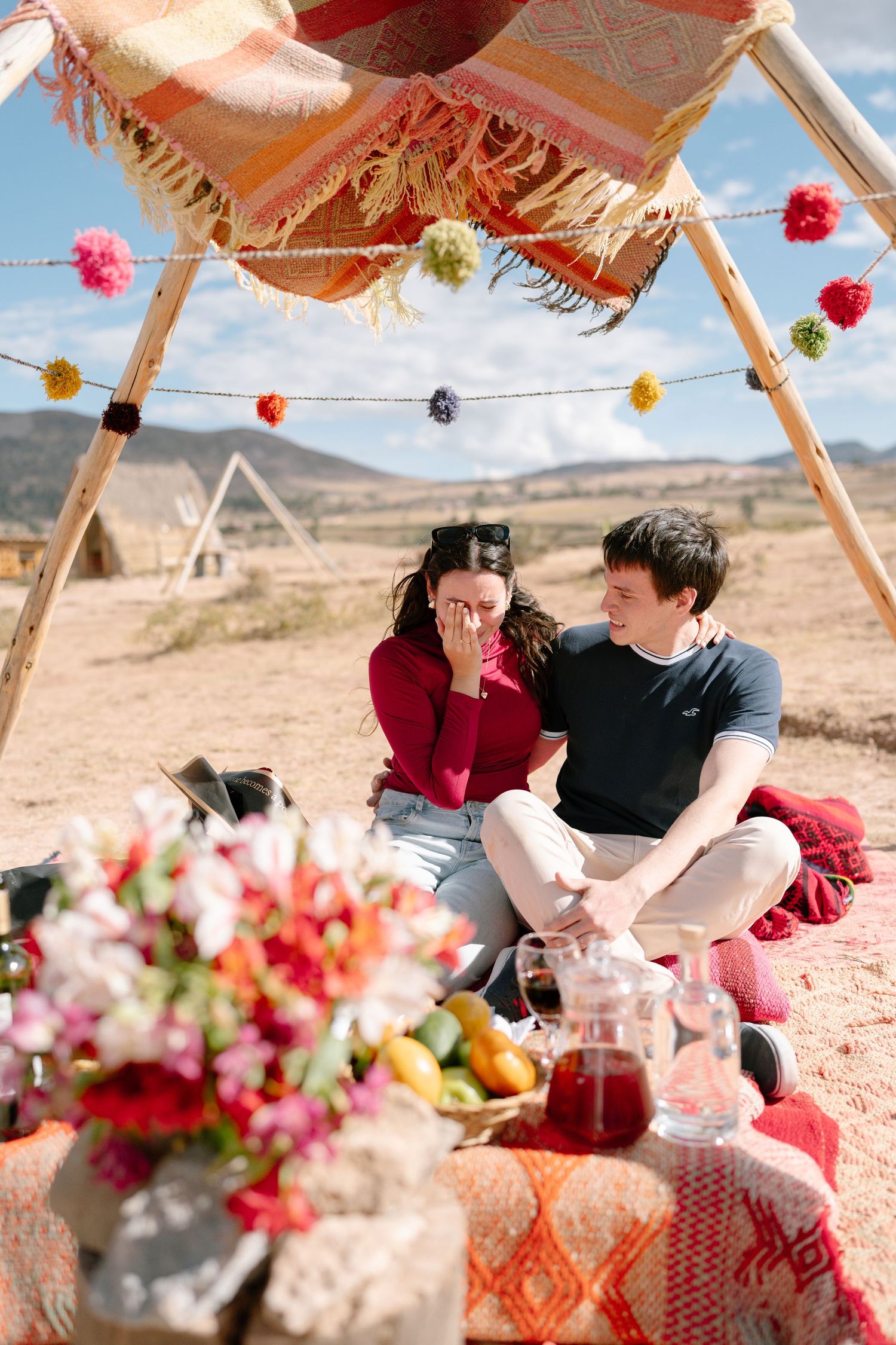 Intimate picnic scene with couple lounging under a decorated canopy in desert setting.