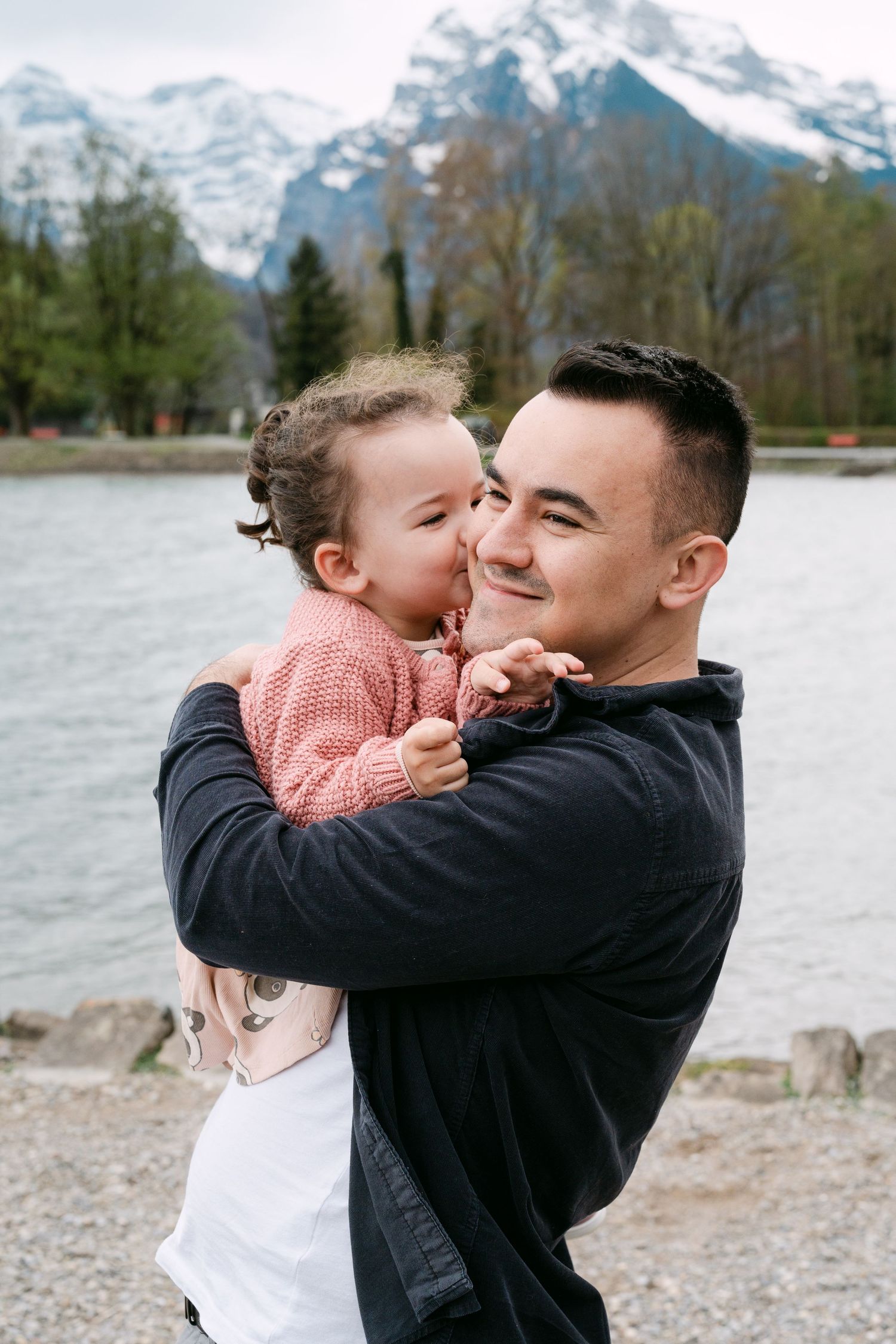 Sweet moments shared between parent and child against a mountainous landscape.
