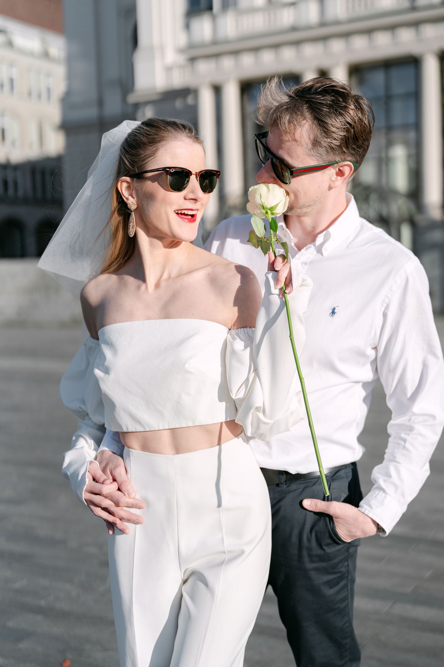 Modern wedding couple sharing playful moments in front of classical architecture.