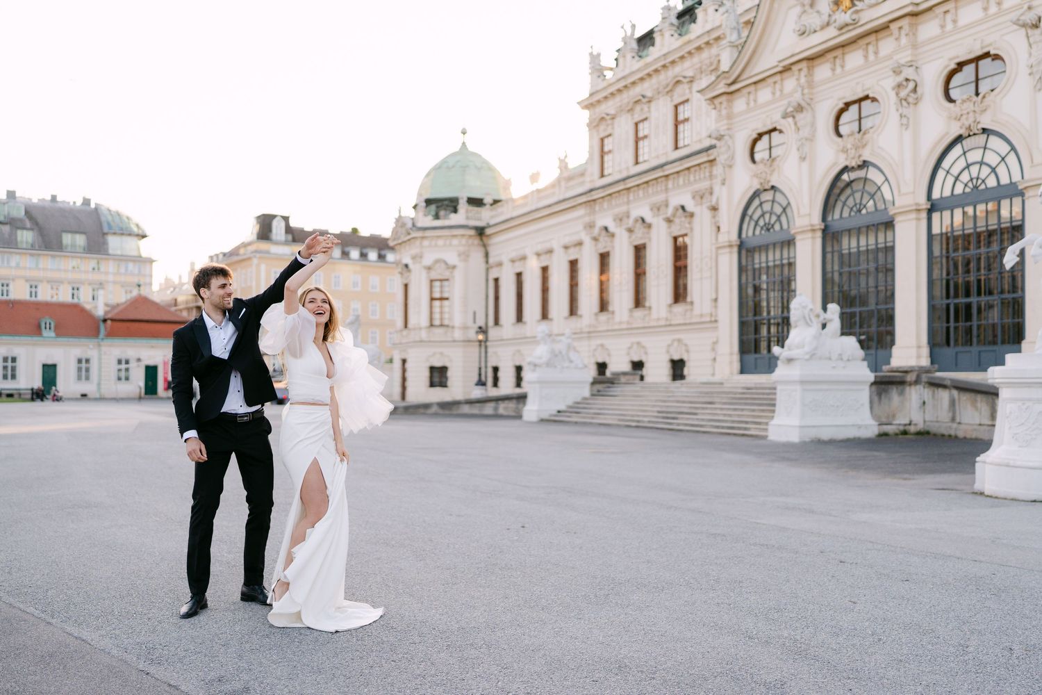 Elegant wedding couple posing in front of historic Viennese palace architecture.