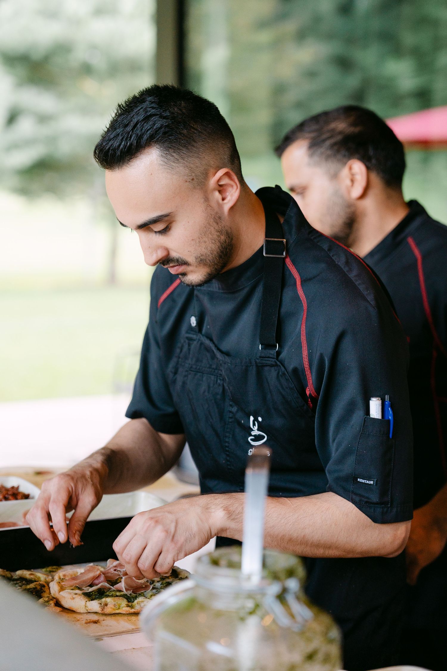 Chefs in black uniforms carefully preparing dishes at an outdoor event.