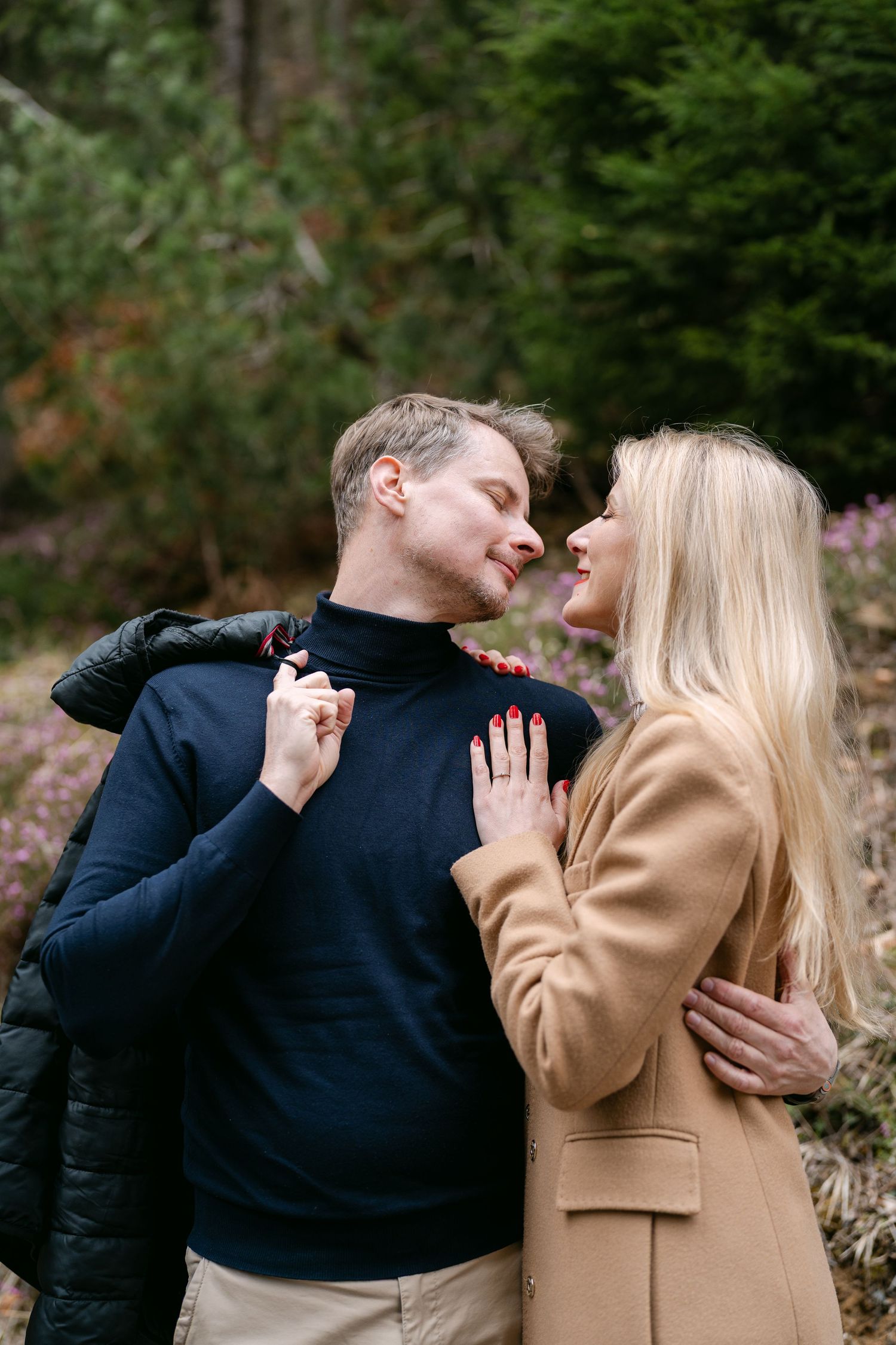 A romantic couple shares an intimate moment outdoors wearing winter clothing.