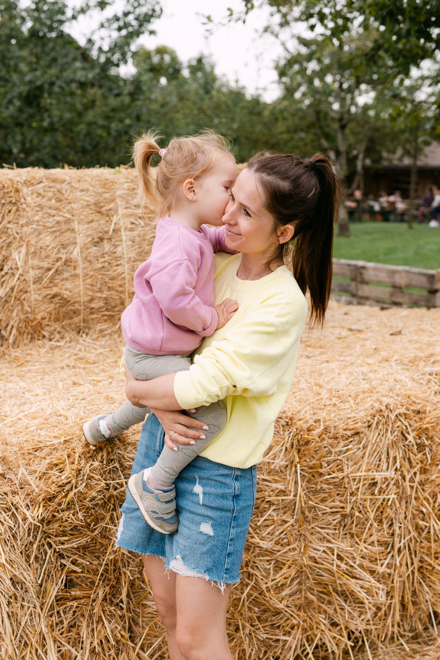 Joyful family moments captured against hay bales in a rustic setting.