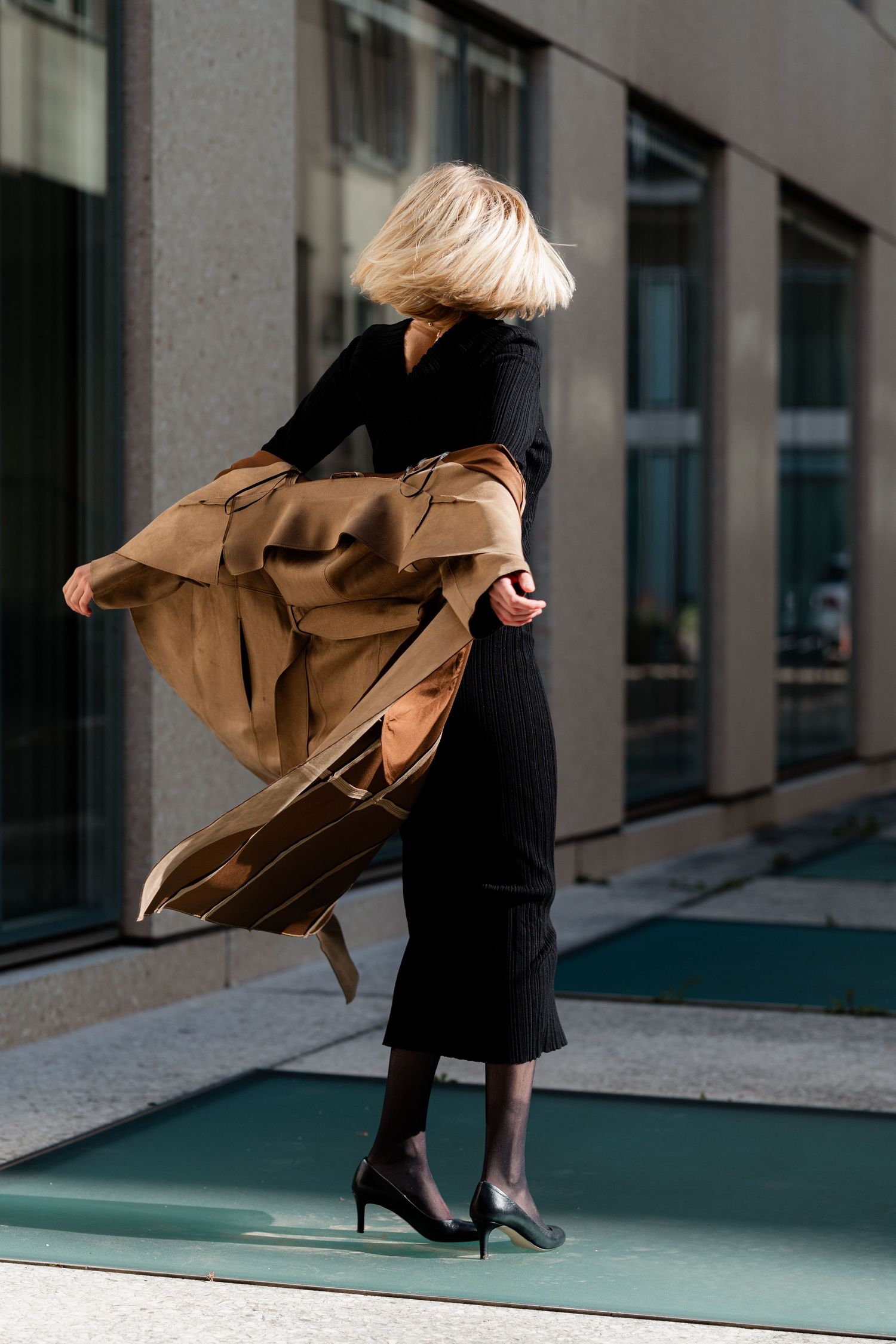Dynamic movement shots of flowing coat against modern architectural backdrop.