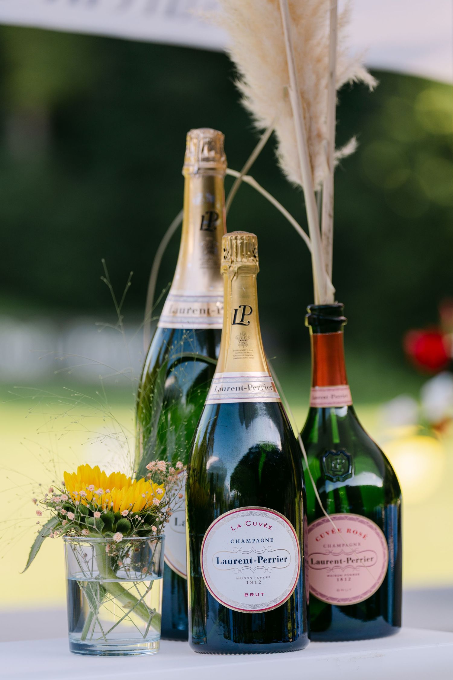Laurent-Perrier champagne bottles elegantly displayed with floral arrangements on an outdoor table.