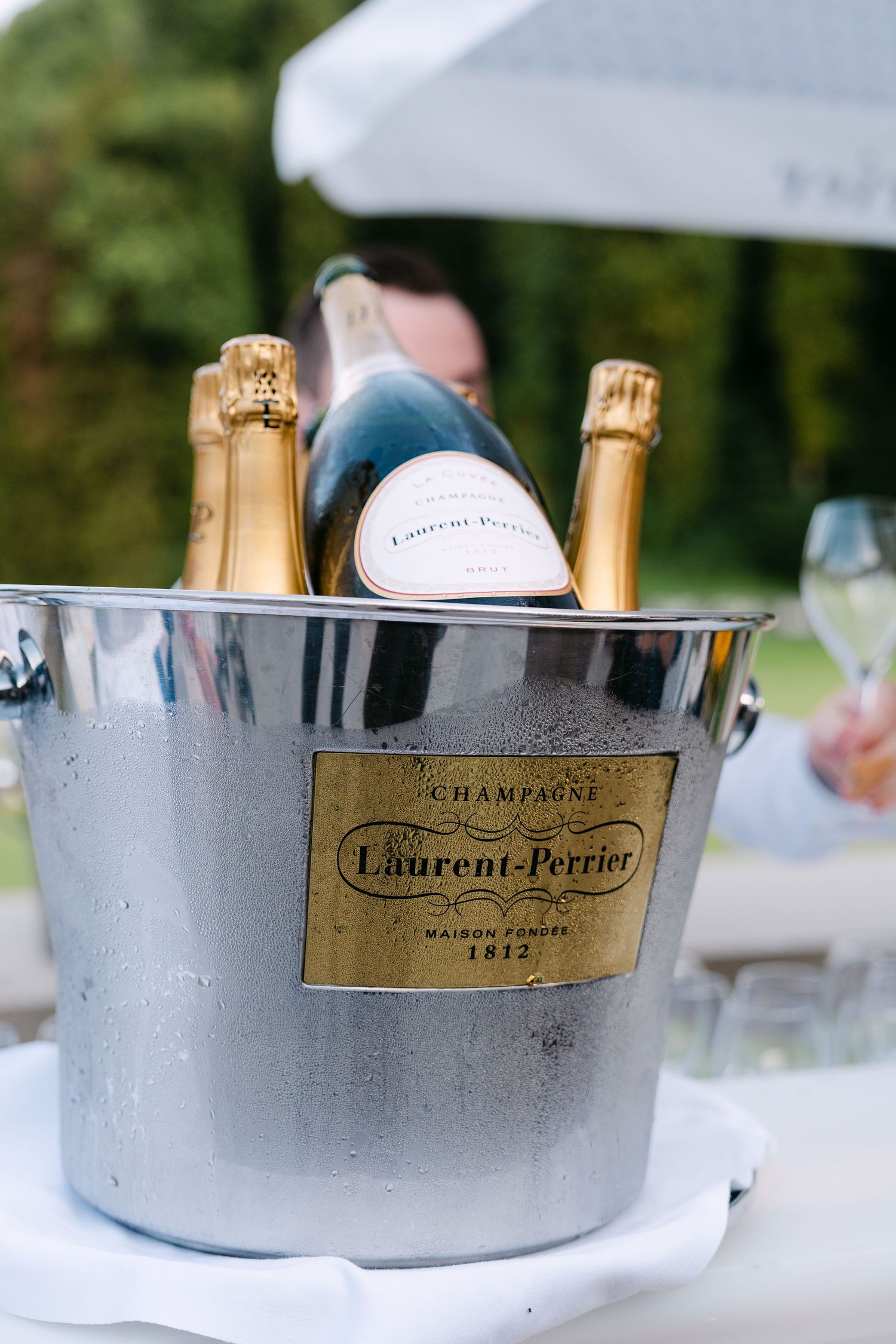 Bottles of Laurent-Perrier champagne chilling in silver ice buckets on a white tablecloth.