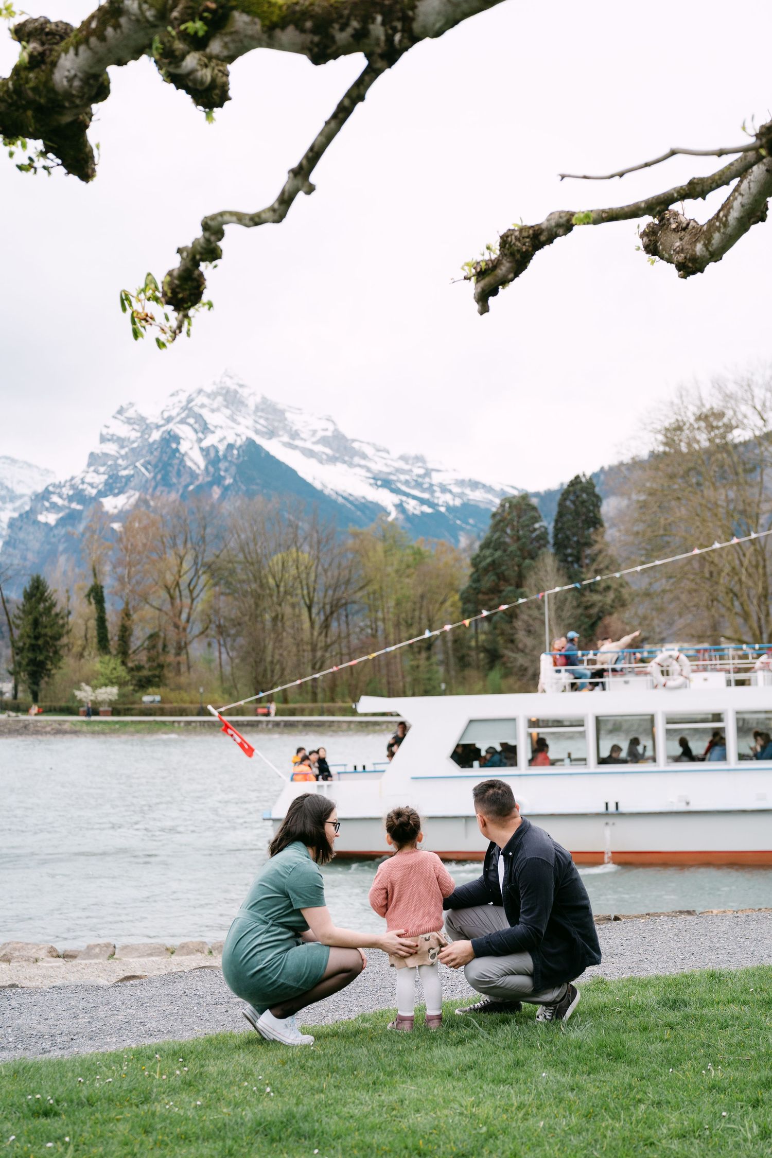 Family spending quality time together on grass near a lake with mountain views.