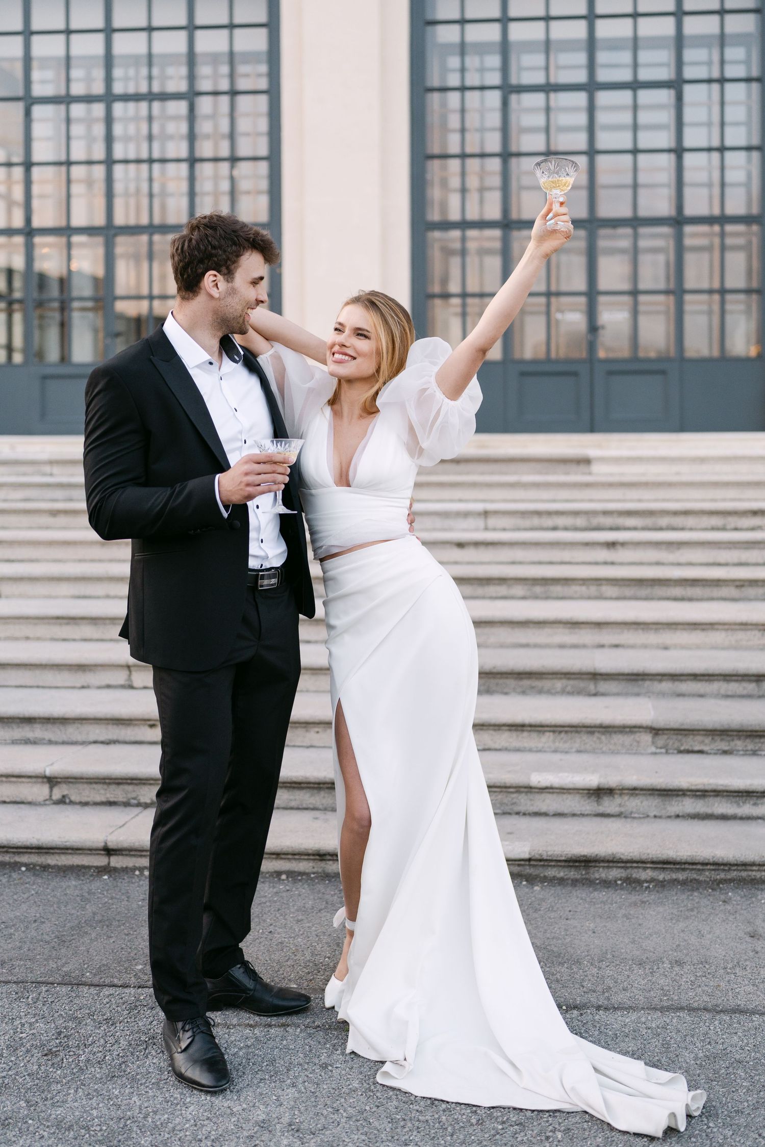 Joyful celebration with champagne on grand building steps.