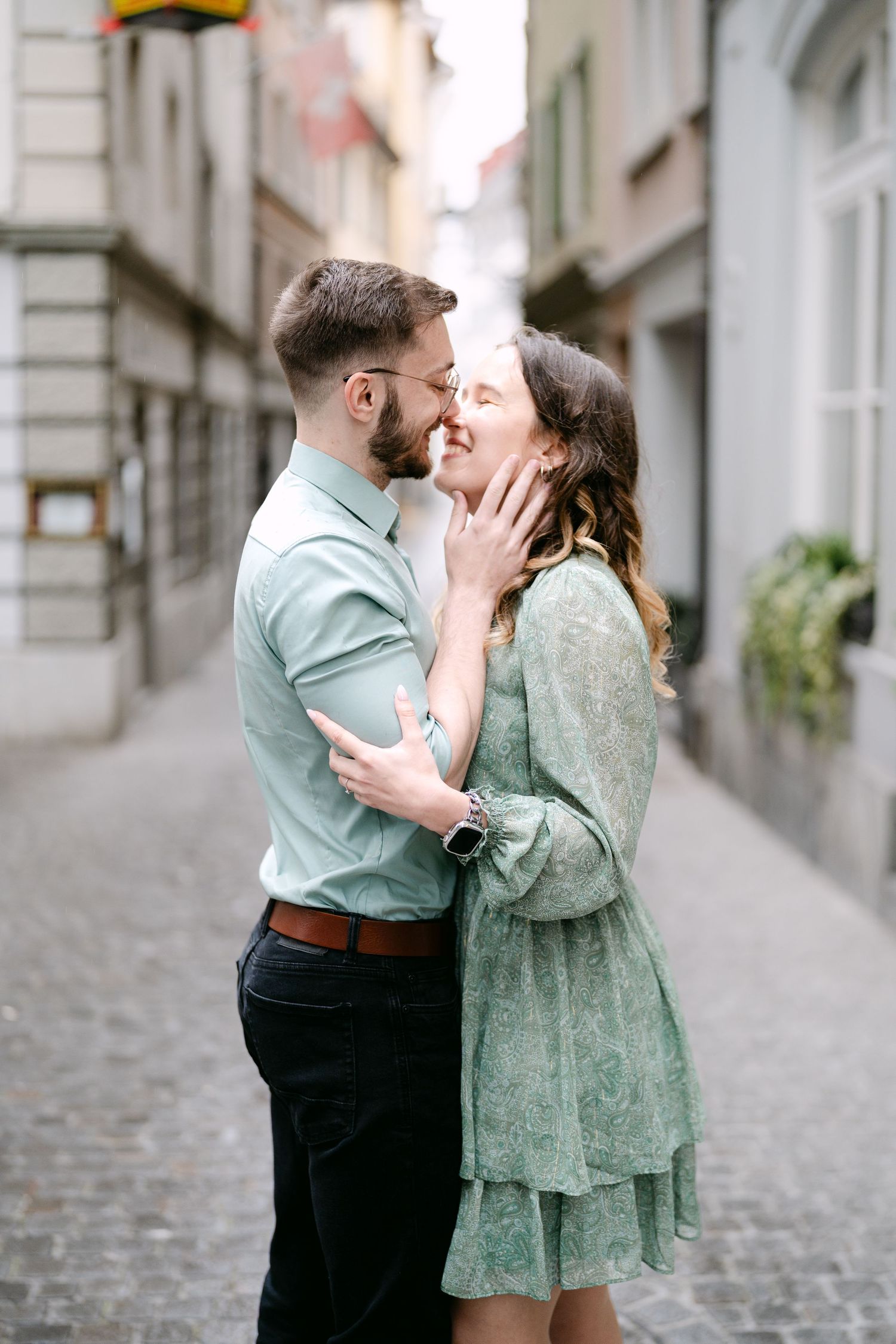 A romantic embrace between a couple on a quaint European street with historic architecture.