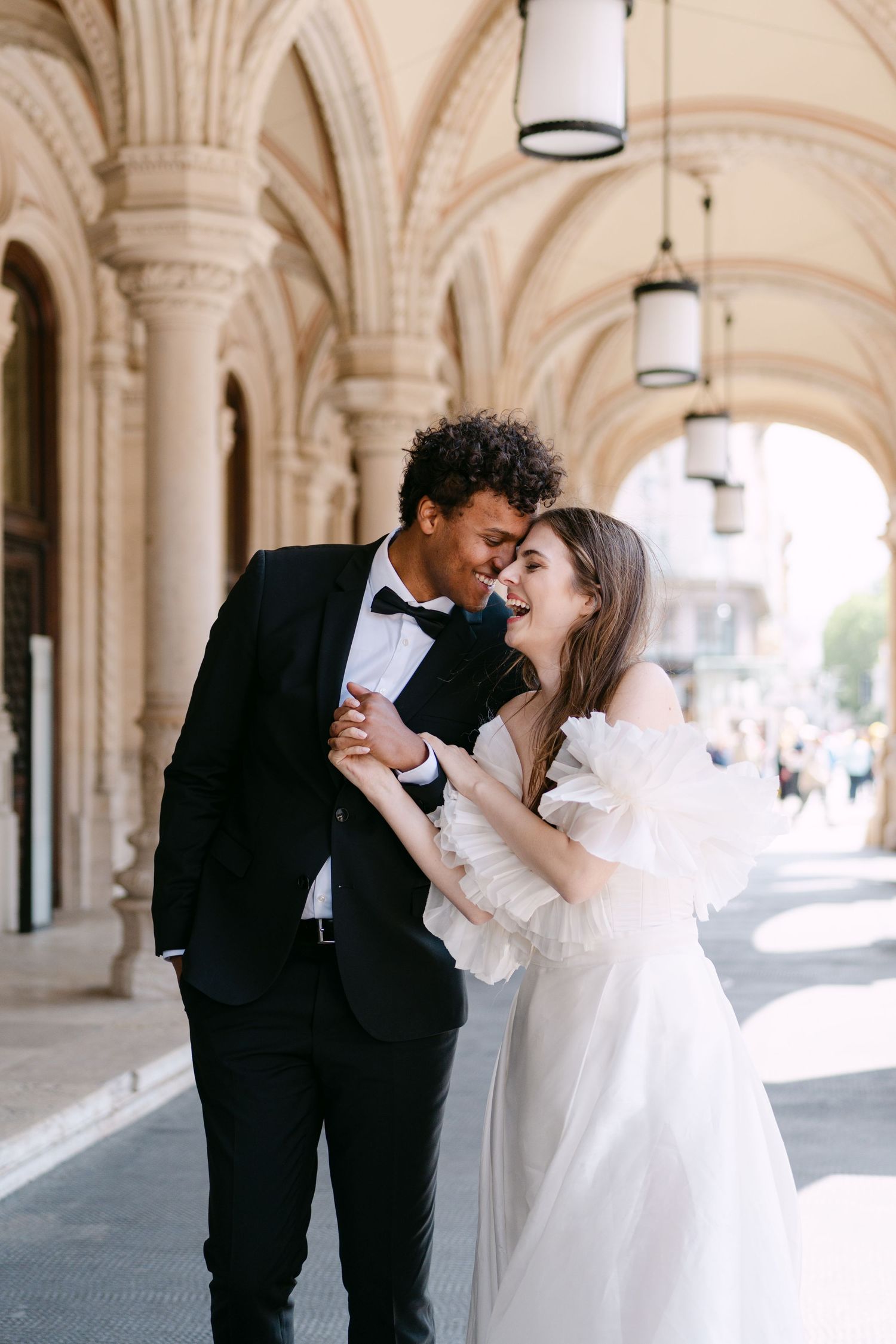 Intimate wedding moment captured under historic arched hallway with natural lighting.