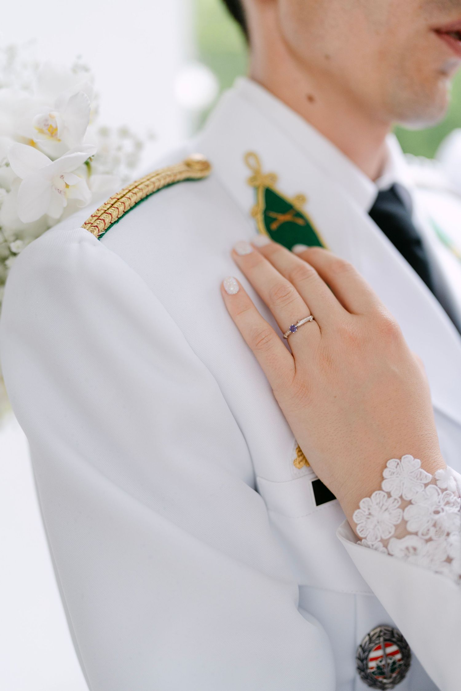 Detail shot of military uniform with medals and rings during wedding photography.