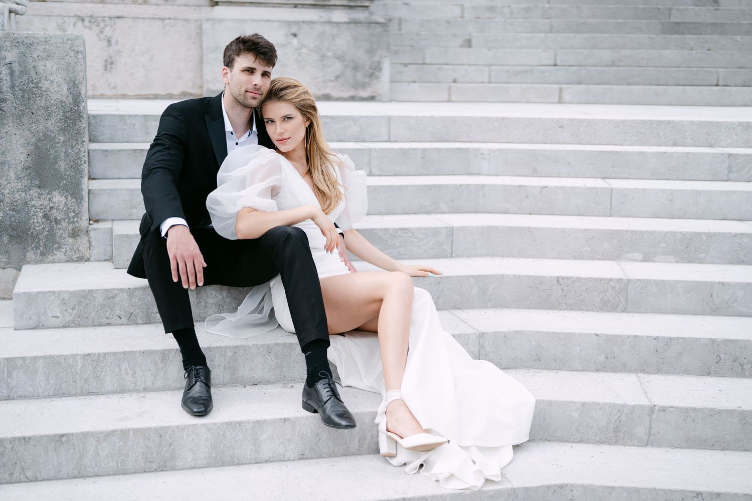 Intimate portrait of a couple in formal wear relaxing on stone steps.