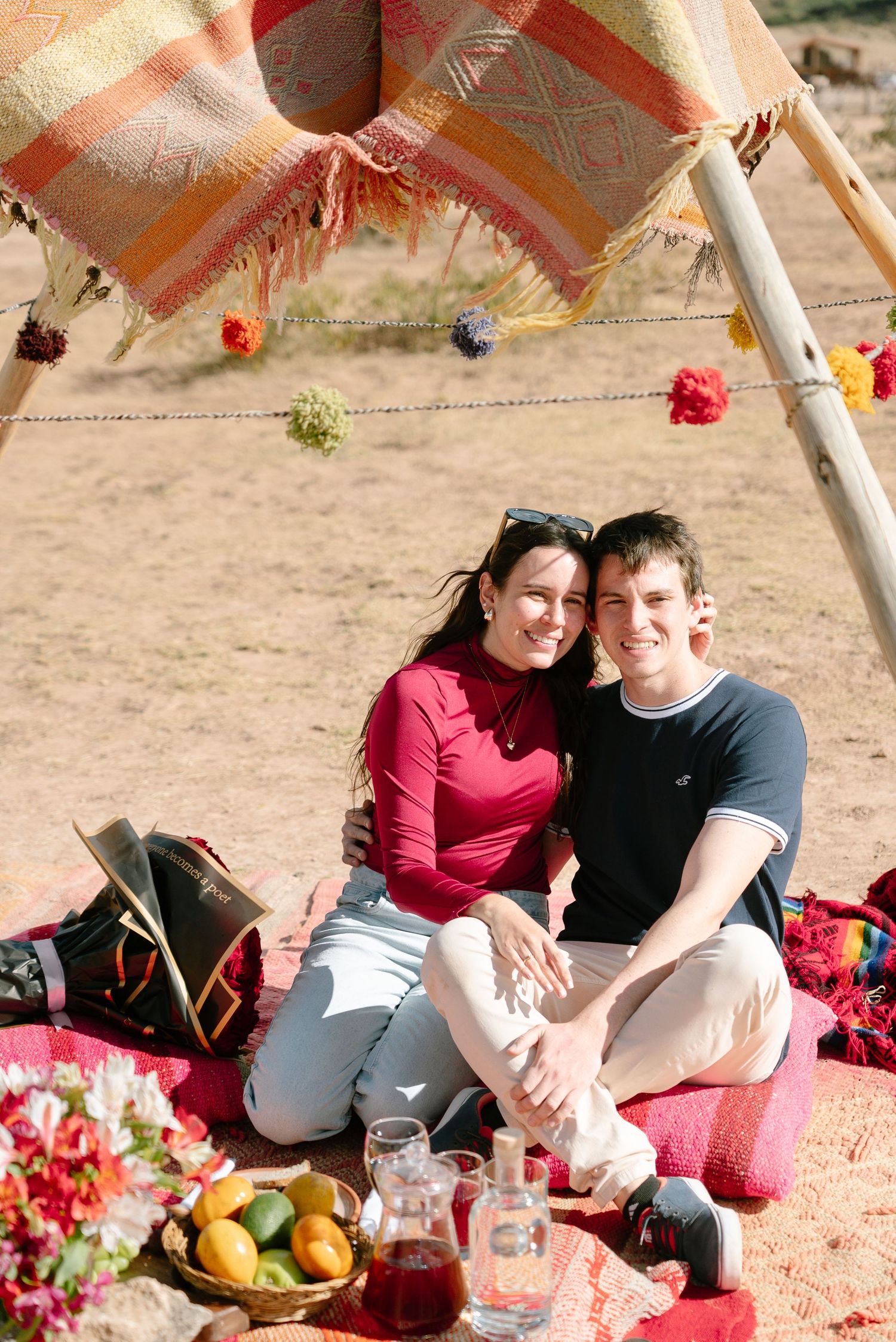 Intimate picnic scene under a decorated canopy with fruit and flowers in the desert.
