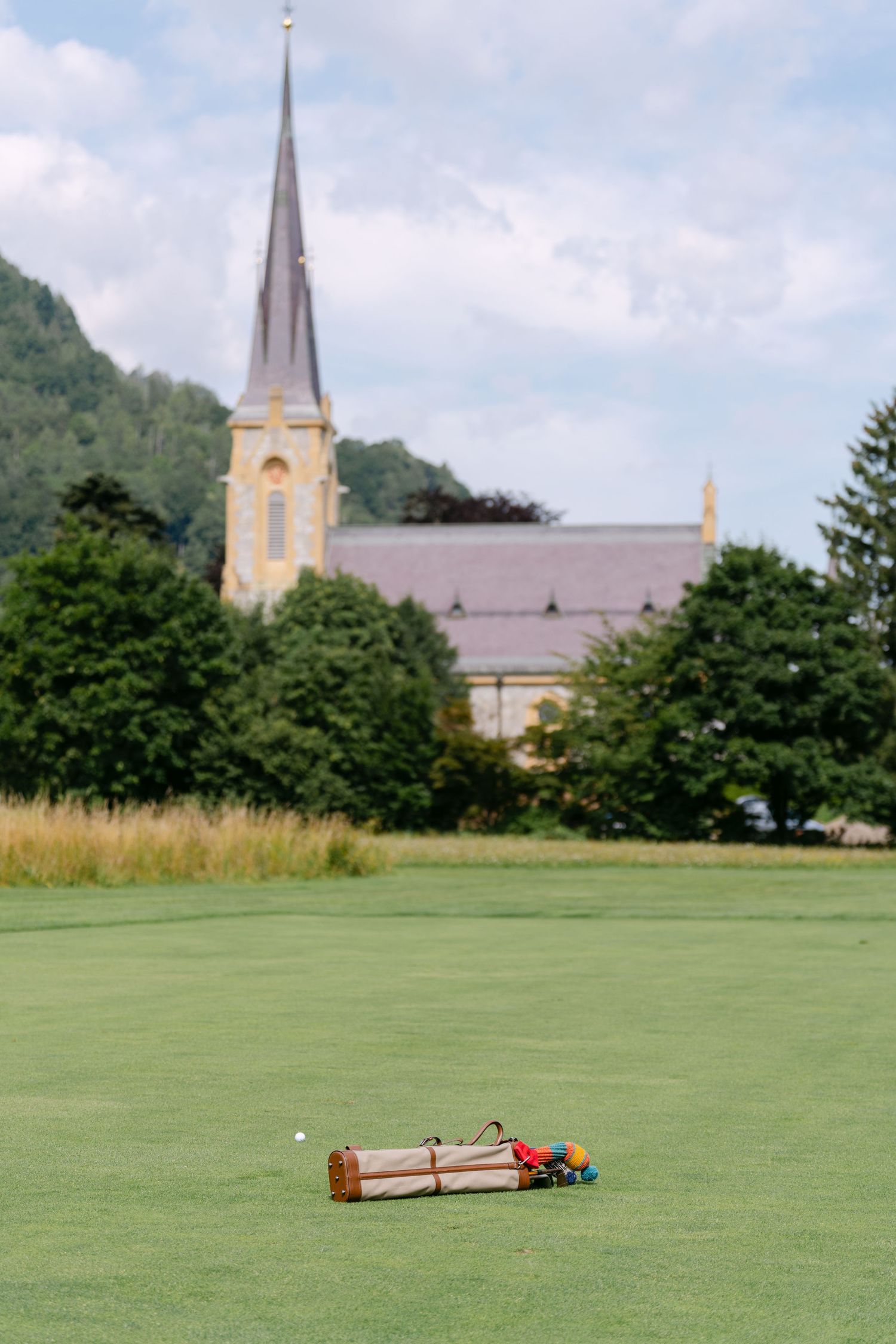 Wooden croquet equipment laid out on a manicured green lawn with church spires in the background.