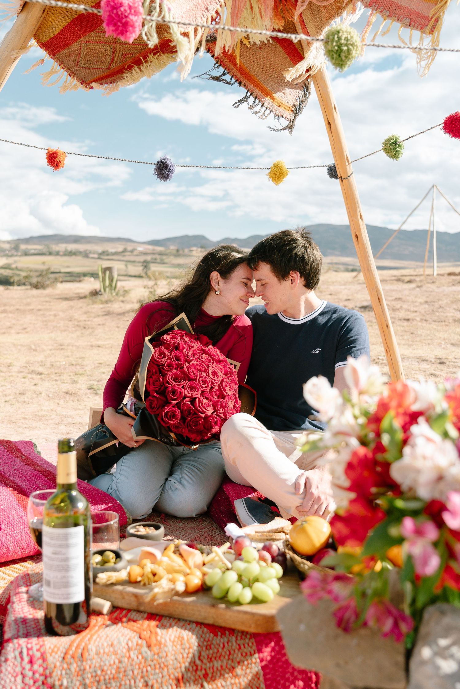 Desert picnic scene with red roses, fresh fruit, and decorative hanging elements.