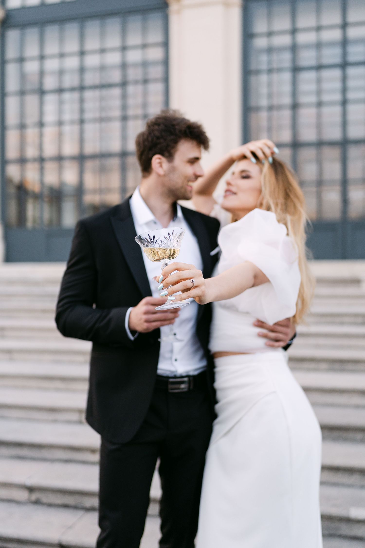 Candid wedding moment shared over drinks on grand stone steps.