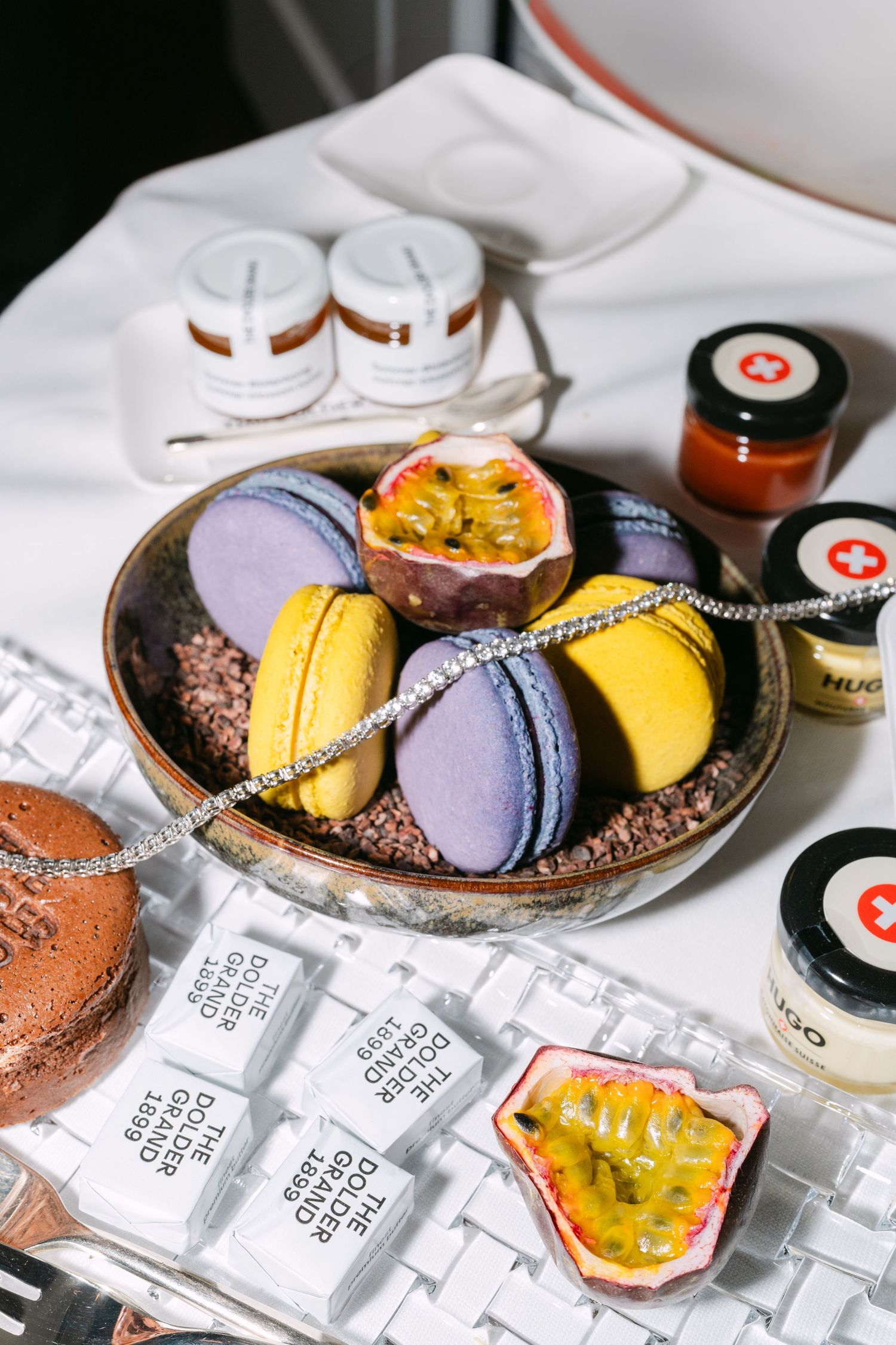 Colorful macarons and desserts arranged on plate with small jars and packaging.